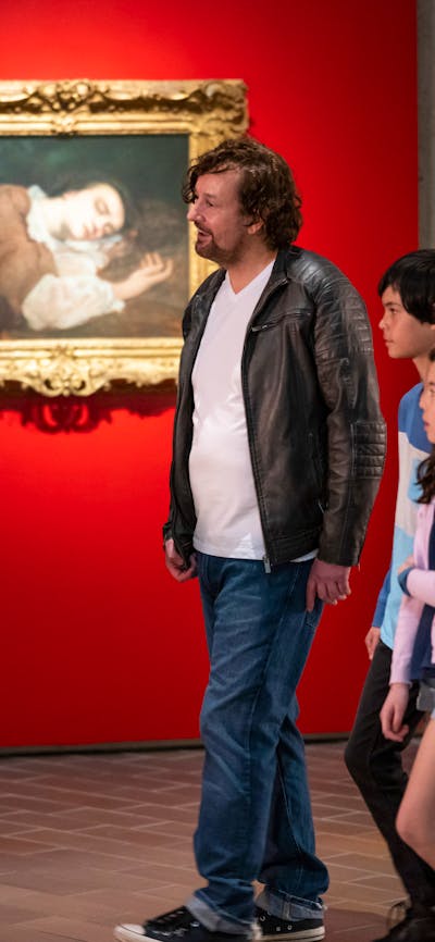 A tour guide and a family in front of a framed artwork in a gallery