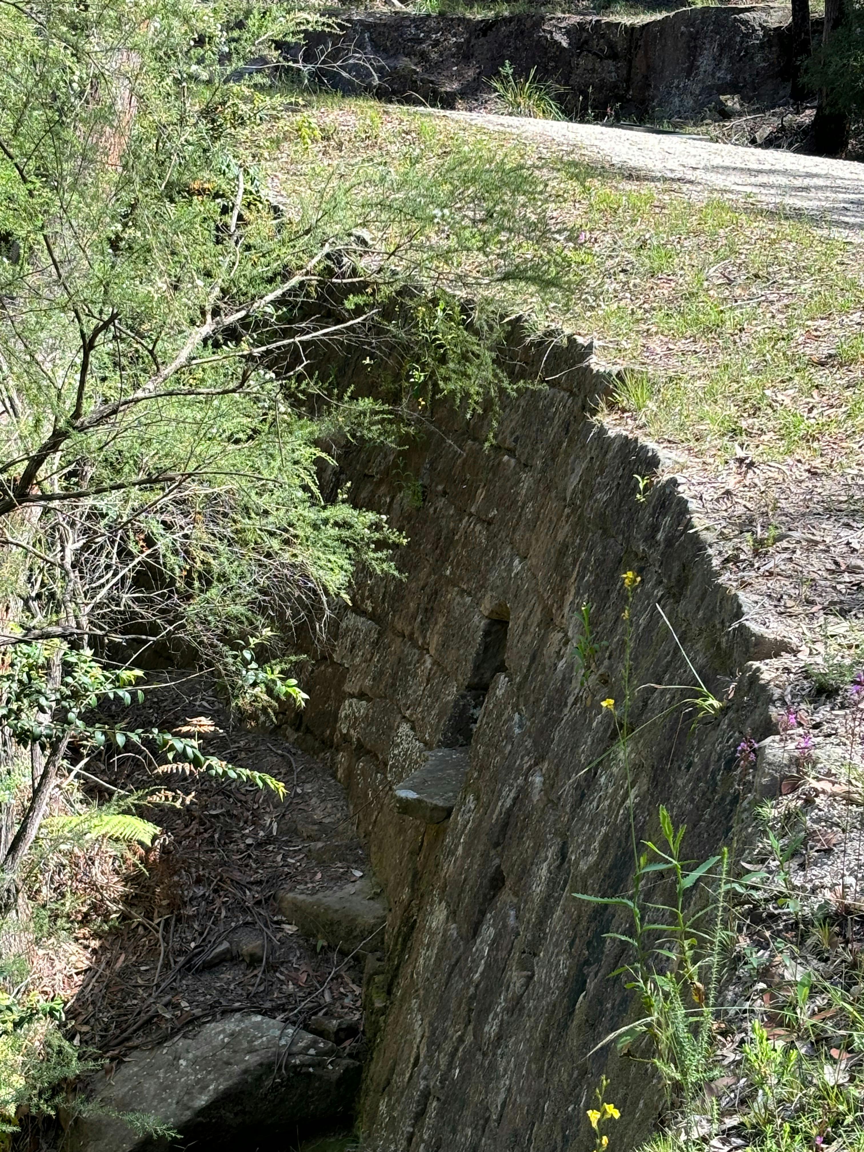 A large stone wall on the edge of a hill supporting a convict-built road.