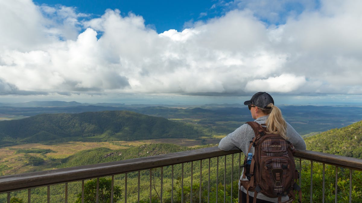 Person at lookout gazes at view over plain and distant mountains.