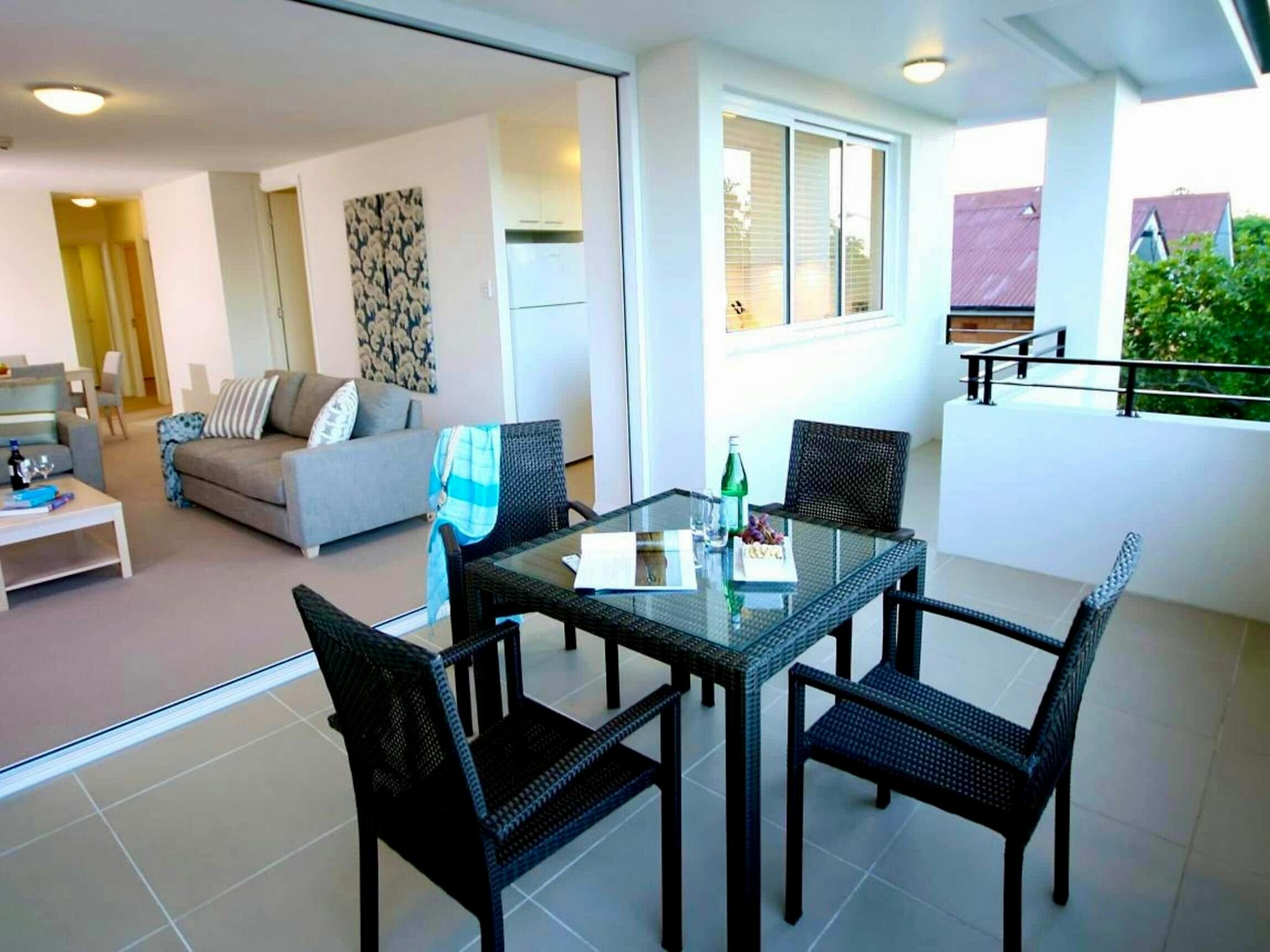 Private balcony with outdoor dining table and four chairs looking into the open-plan living and dini Private balcony with outdoor dining table and four chairs looking into the open-plan living and dini