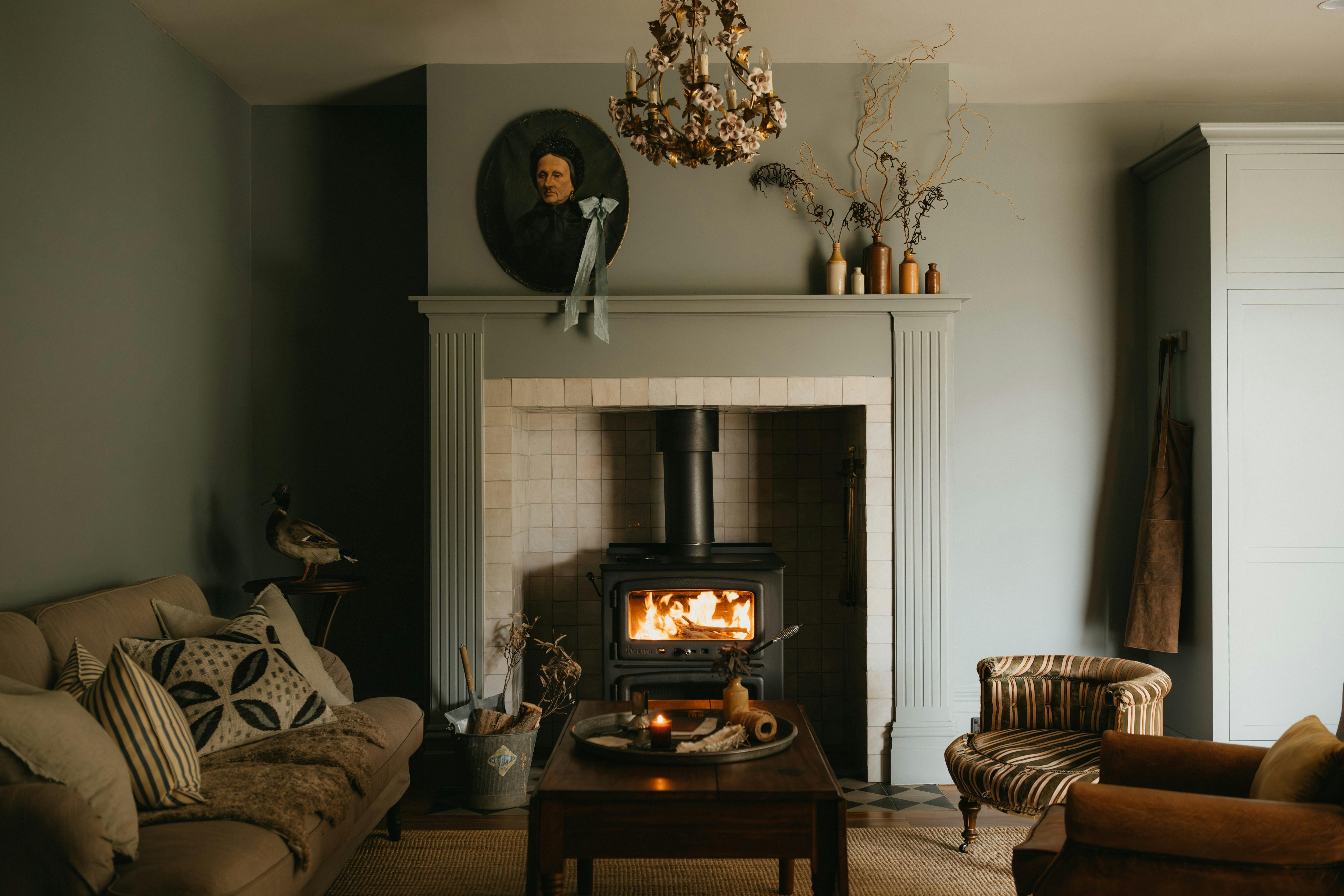 Living room with wood heater, sofa, antique decor and soft natural light.