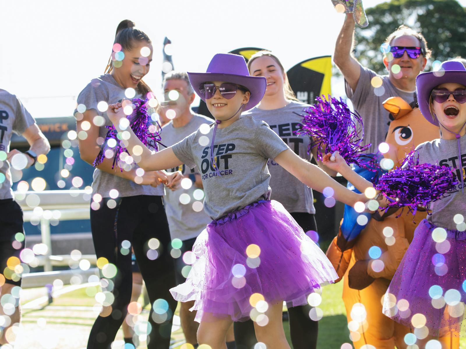 Kids dancing in costumes with bubbles having fun at Step Out for Cancer