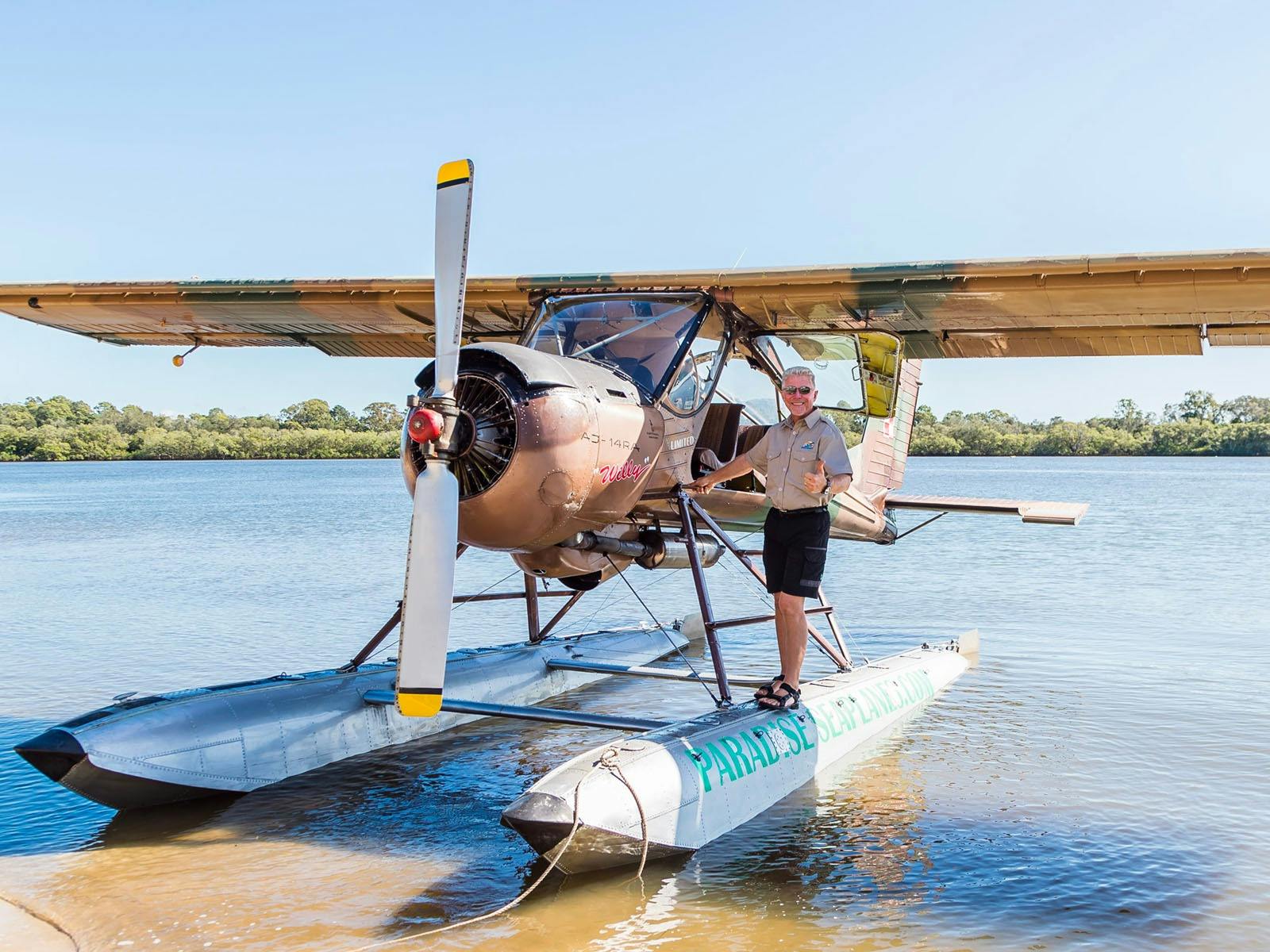 Pilot stands on float of Wilga seaplane and gives a thumbs up