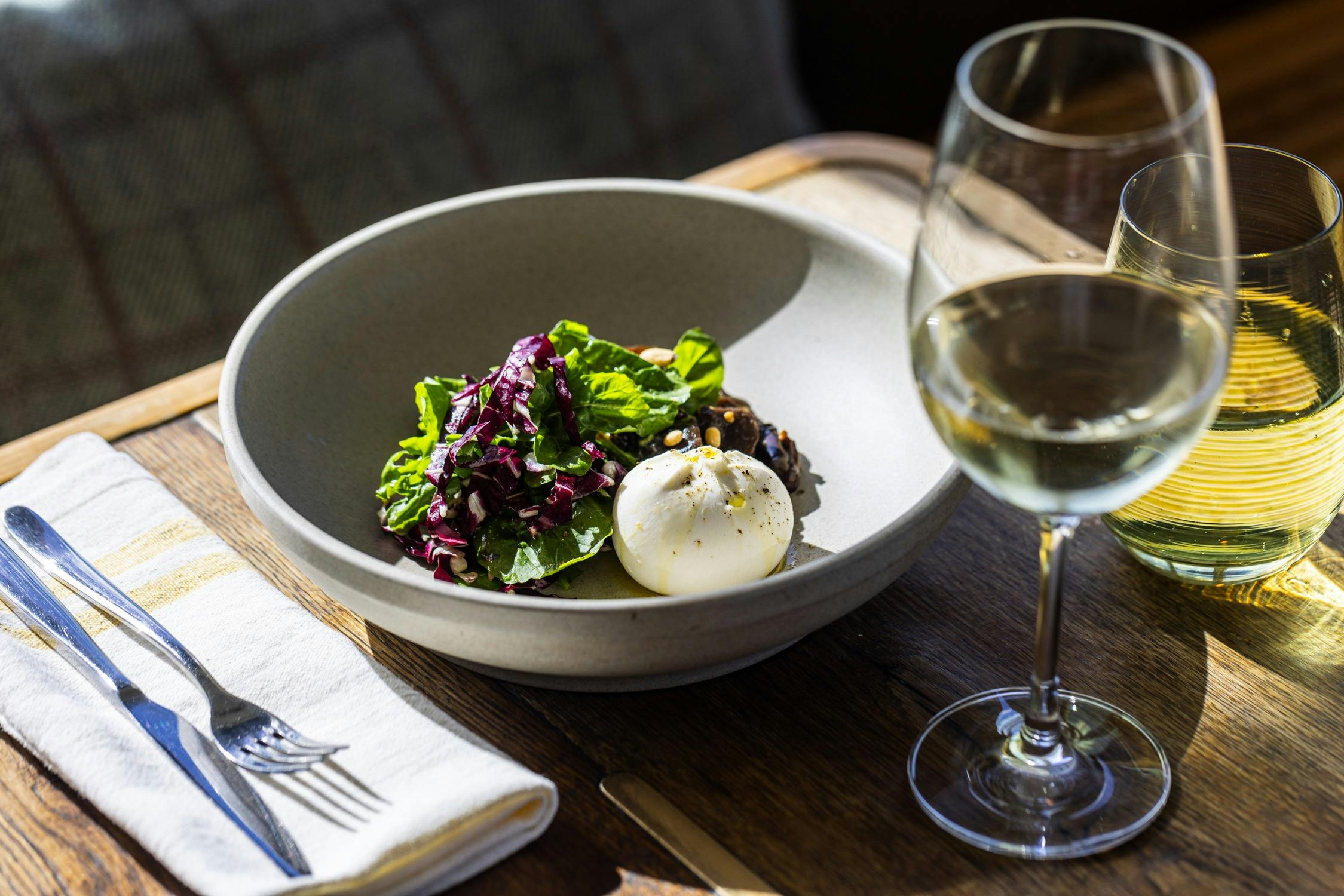 테이블에 놓인 샐러드와 와인 한 잔이 담긴 점심 접시