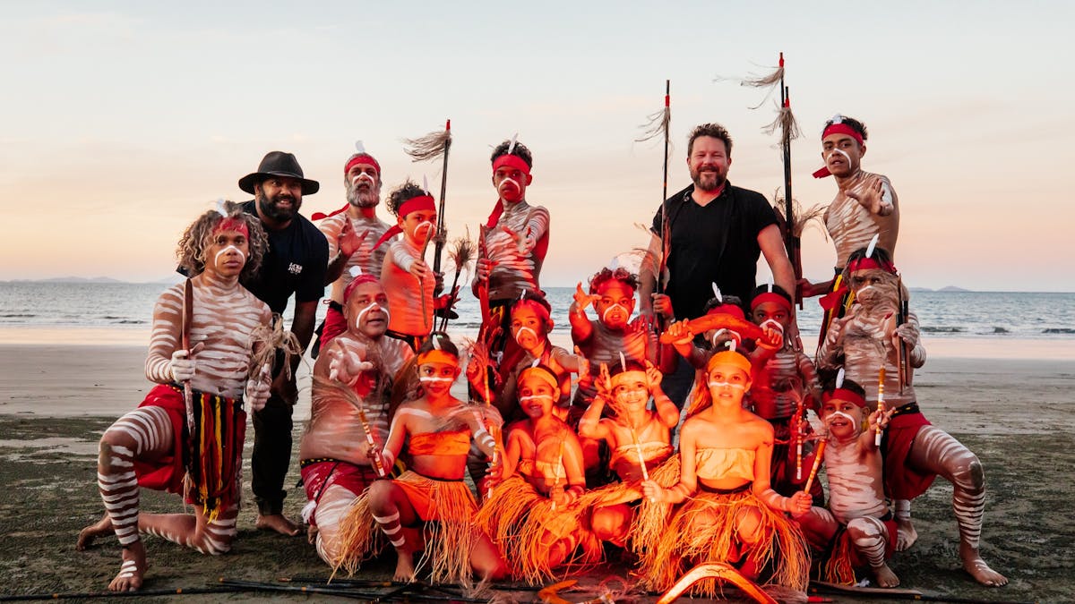 The multi-generational Tchundal Malar Dance Troupe  posing for a photo on the beach