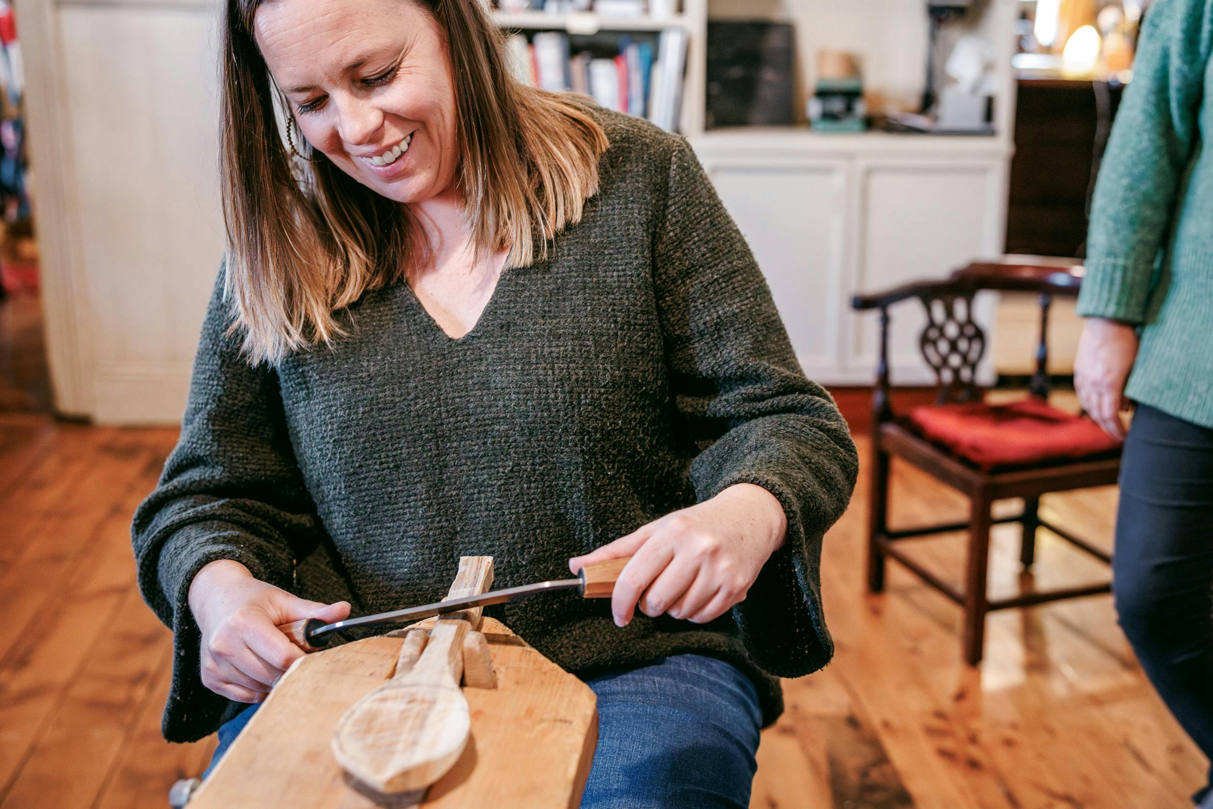 A woman carving a spoon