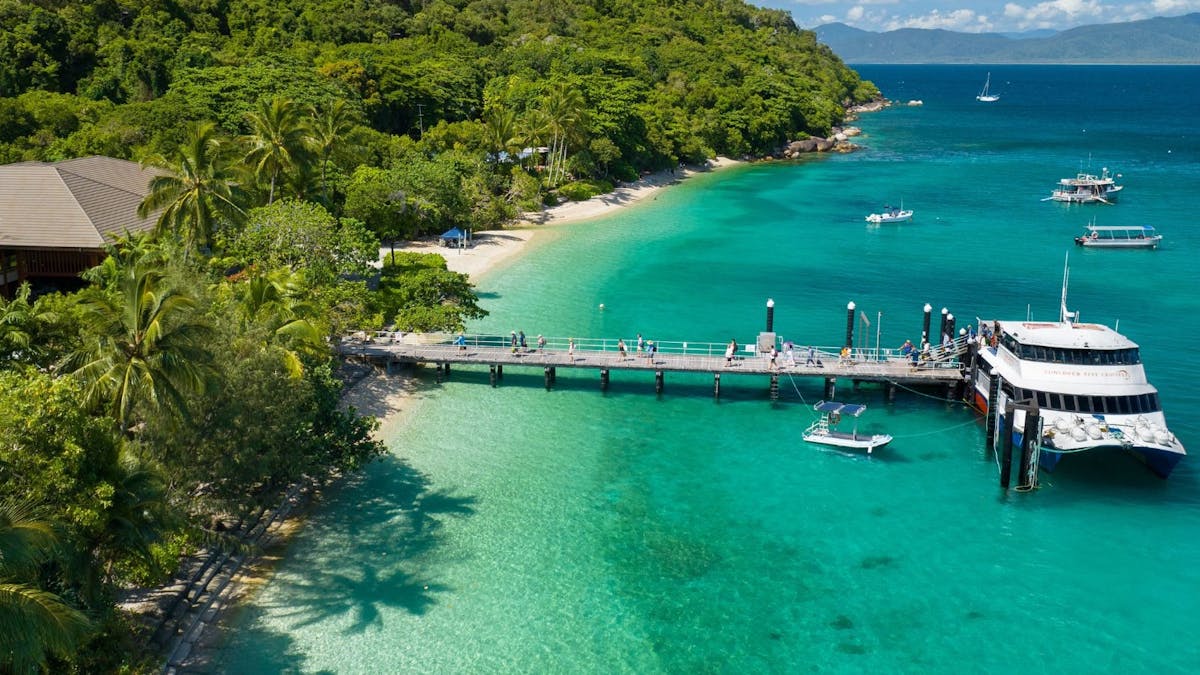 Sunlover Reef Cruises boat docked at the jetty on Fitzroy Island with tropical surroundings.