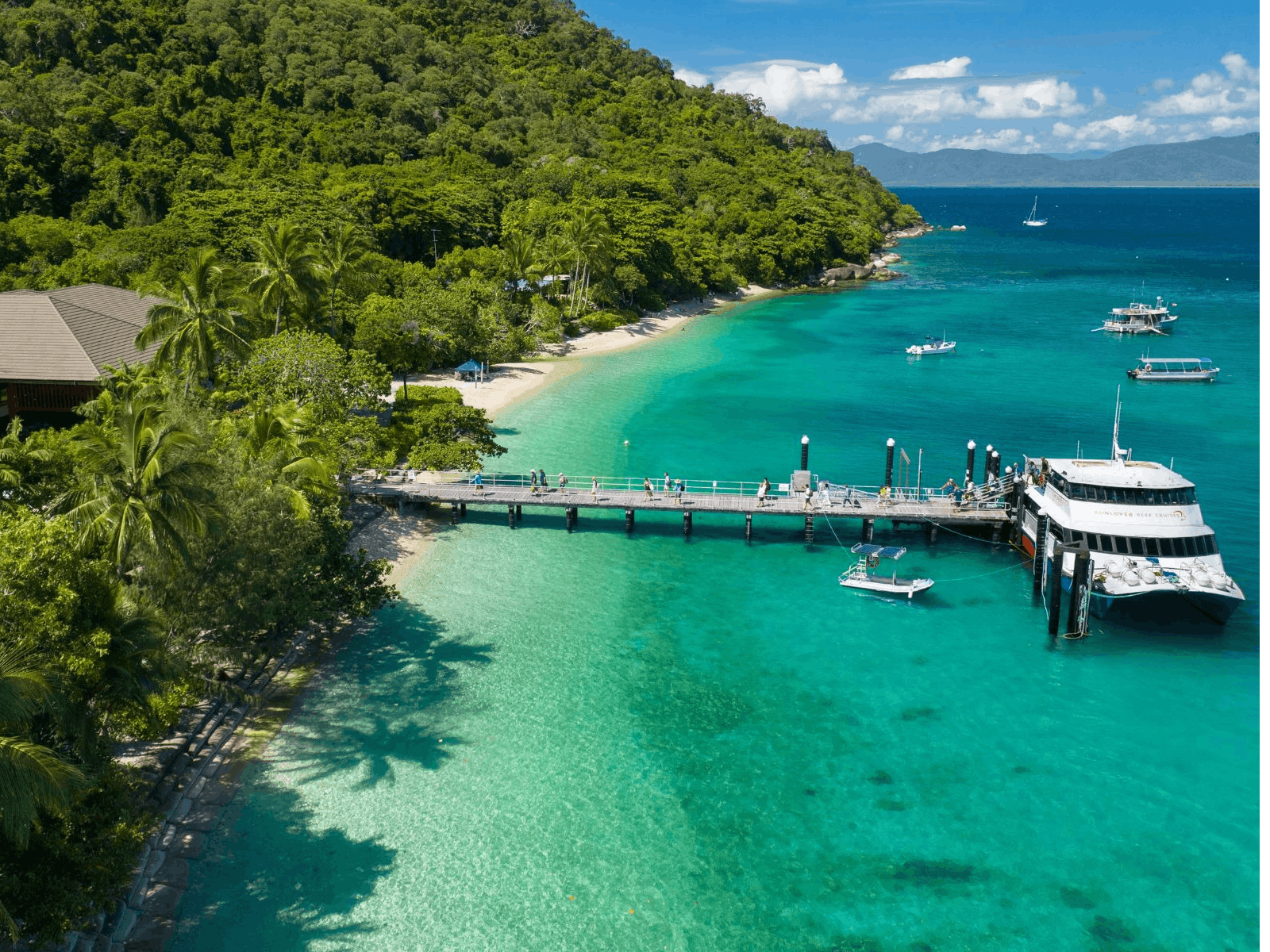 Sunlover Reef Cruises boat docked at the jetty on Fitzroy Island with tropical surroundings.