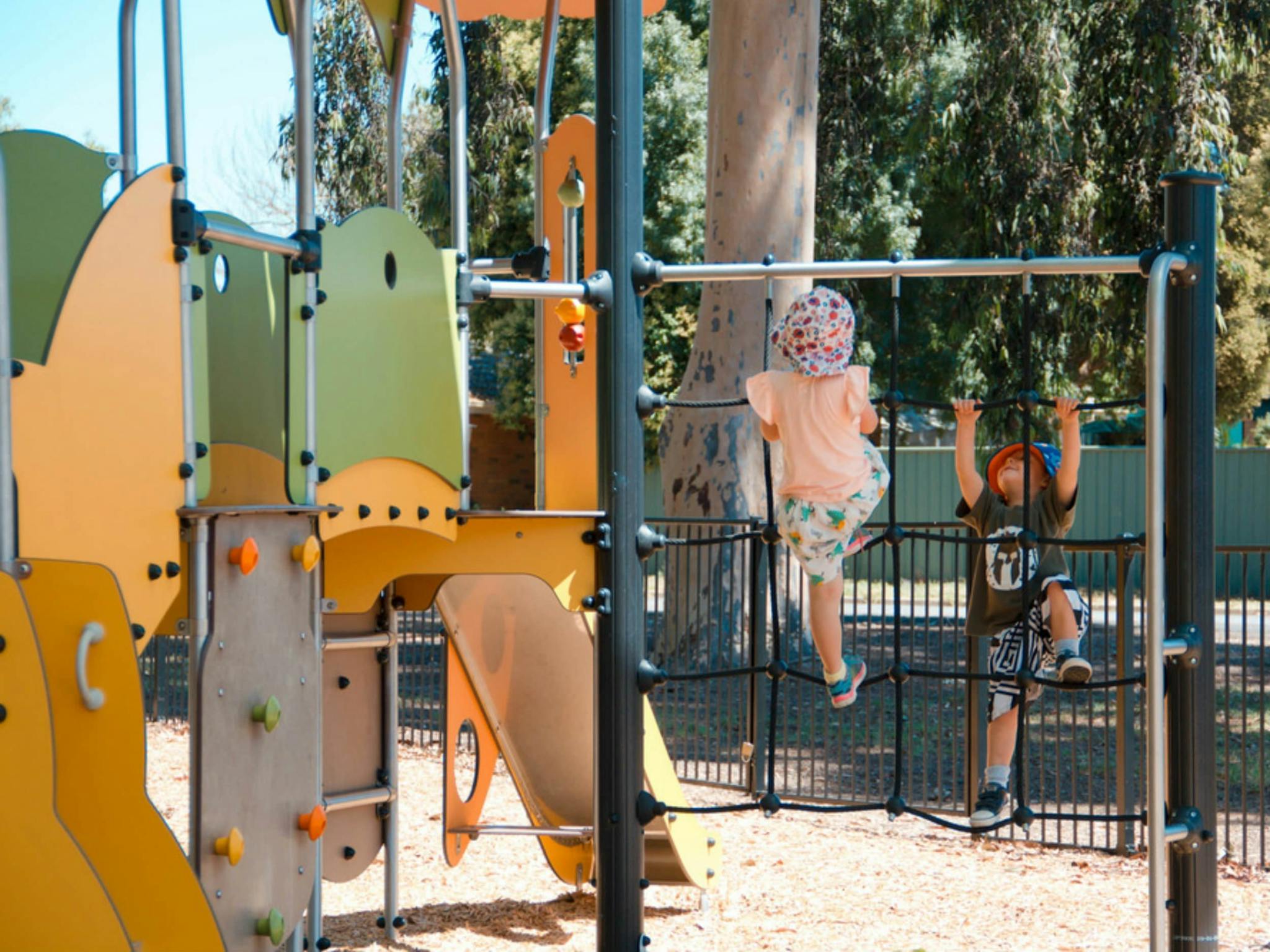 playground with children climbing on rope frame, slide and in the background gum tree