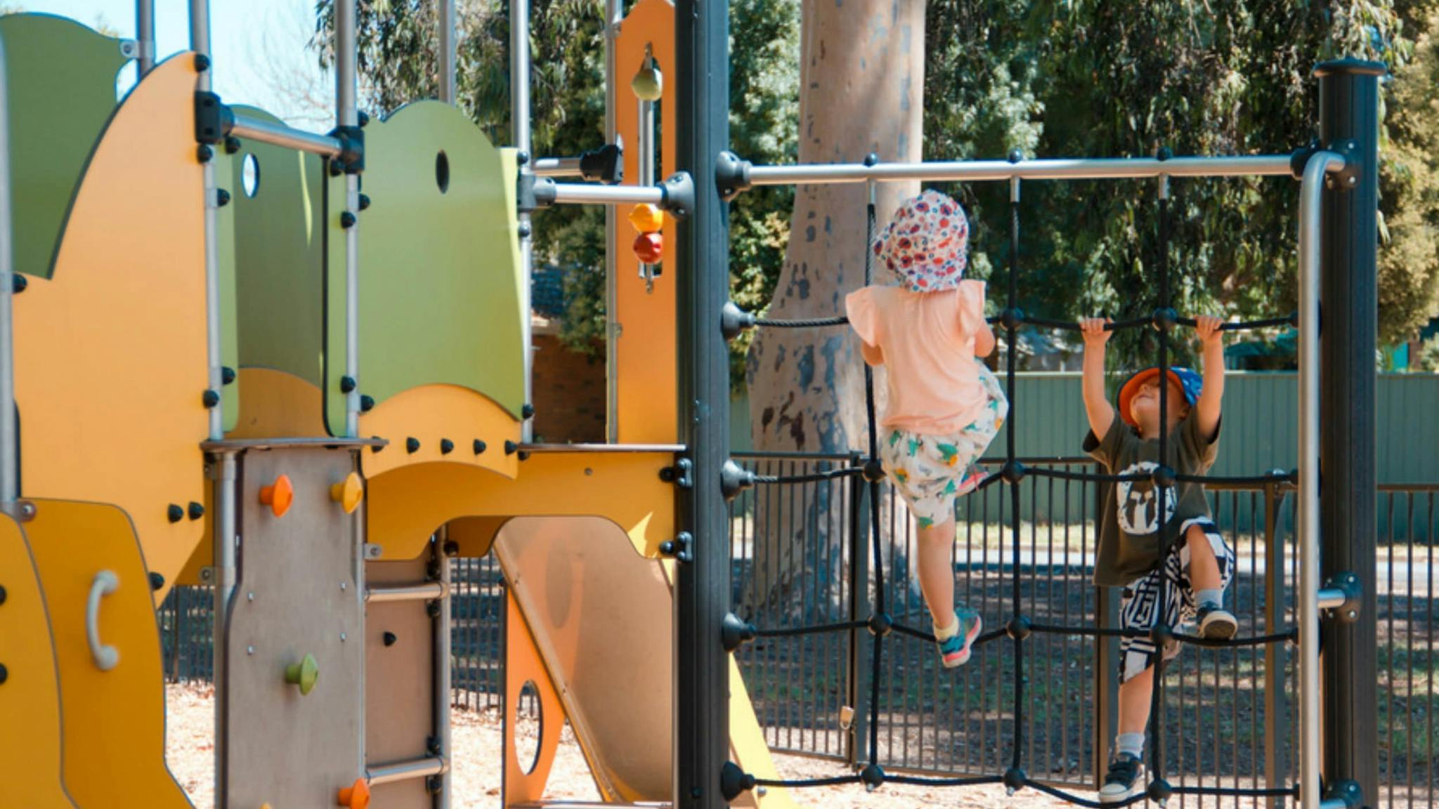 playground with children climbing on rope frame, slide and in the background gum tree