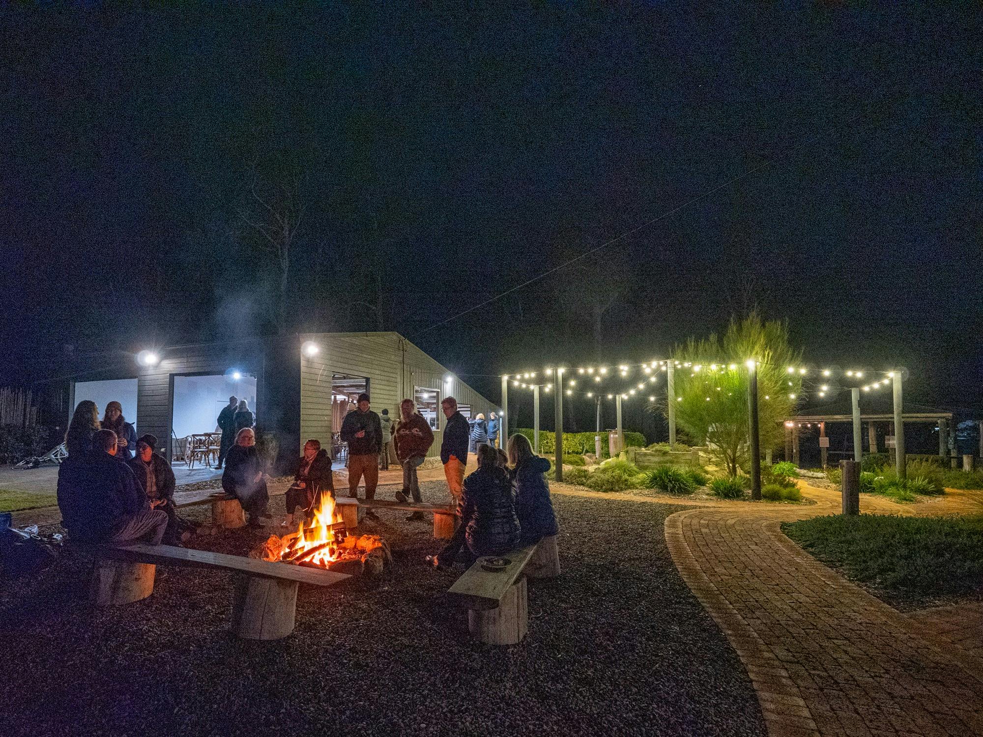 Guests enjoying pizza by open camp fire