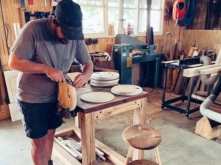 Andy uses hand tools to carve stool seats.