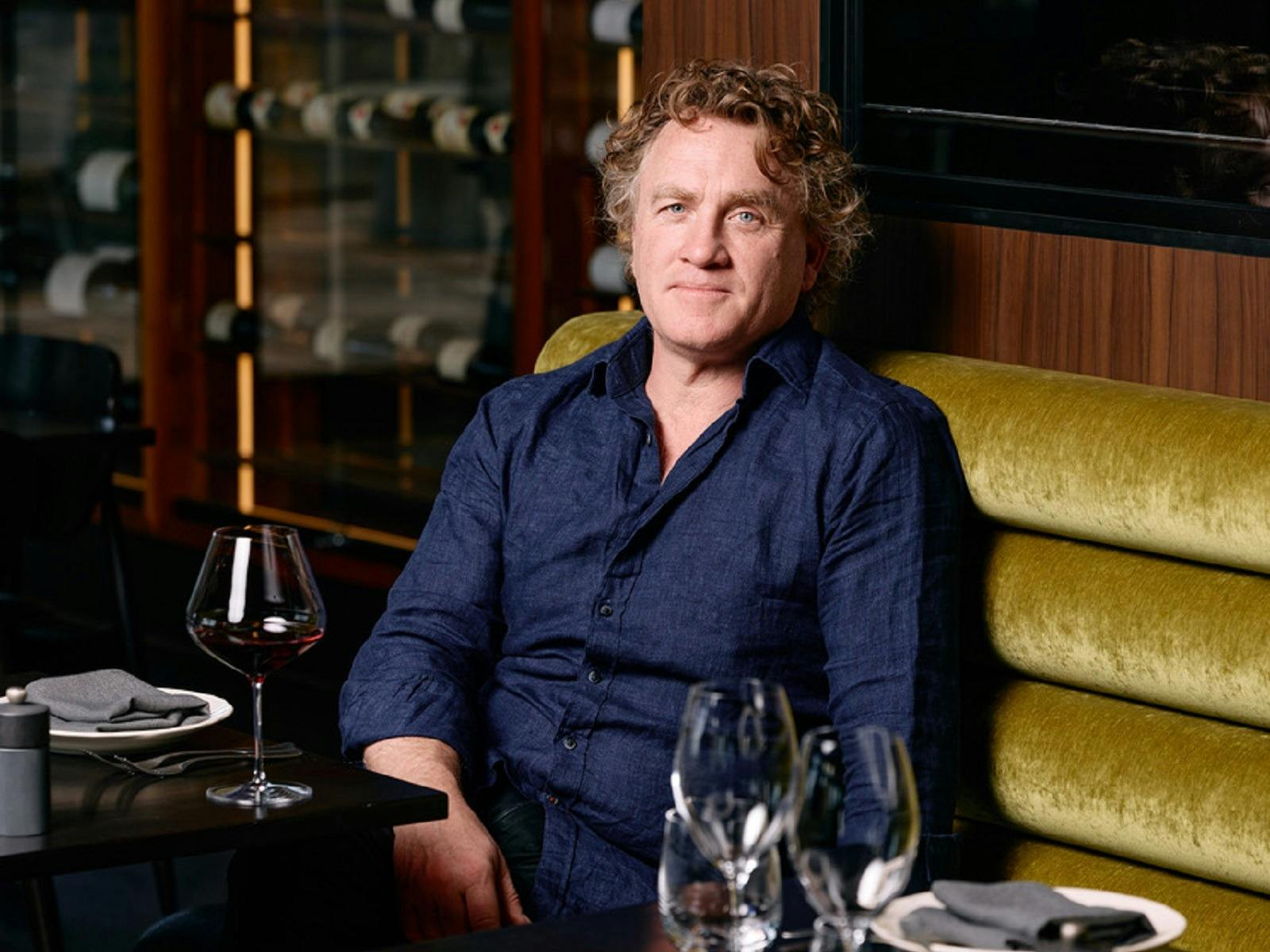 Chef Adrian Richardson looking at the camera with a wine glass
