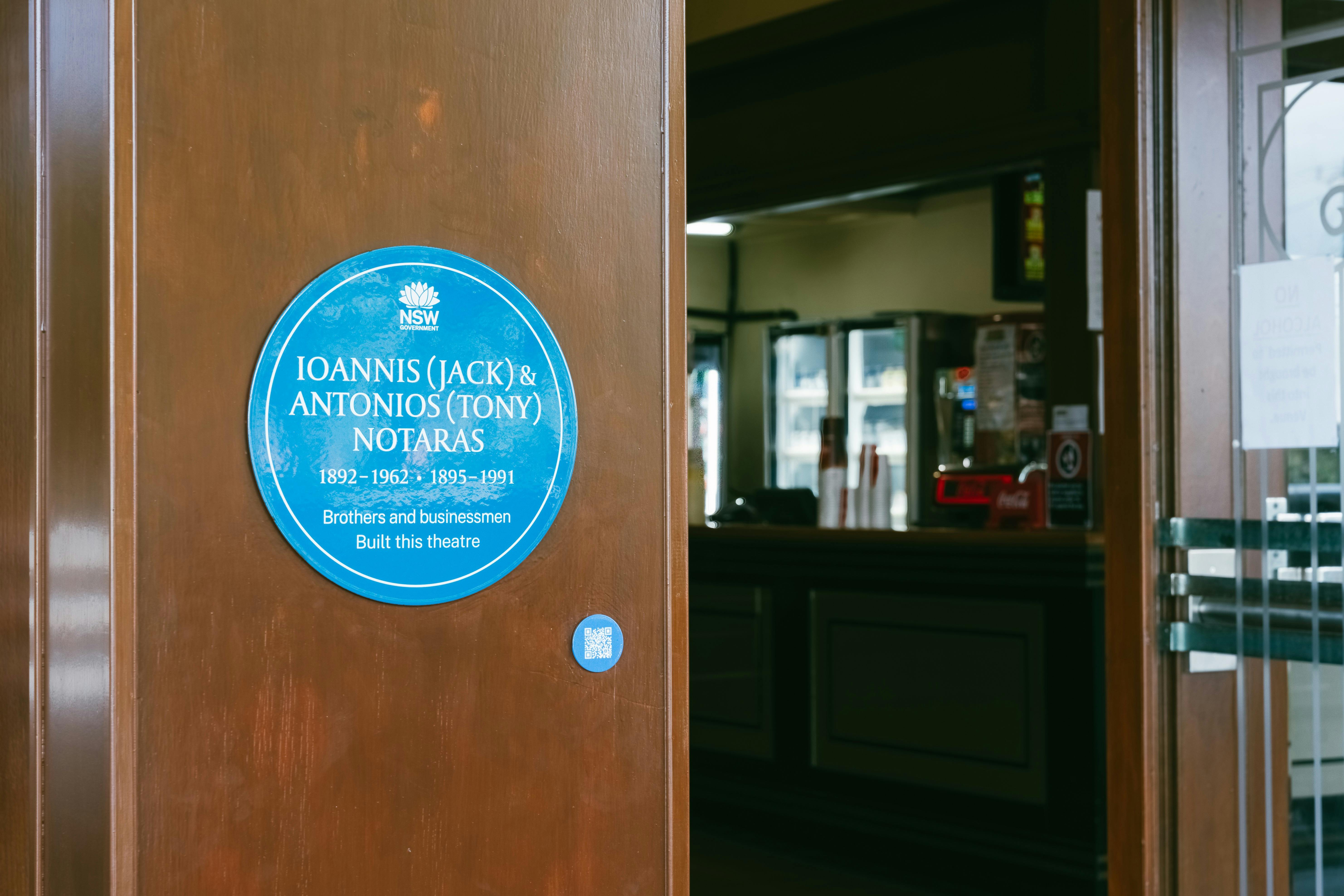 Blue plaque on wooden panel of shopfront leading into bar area