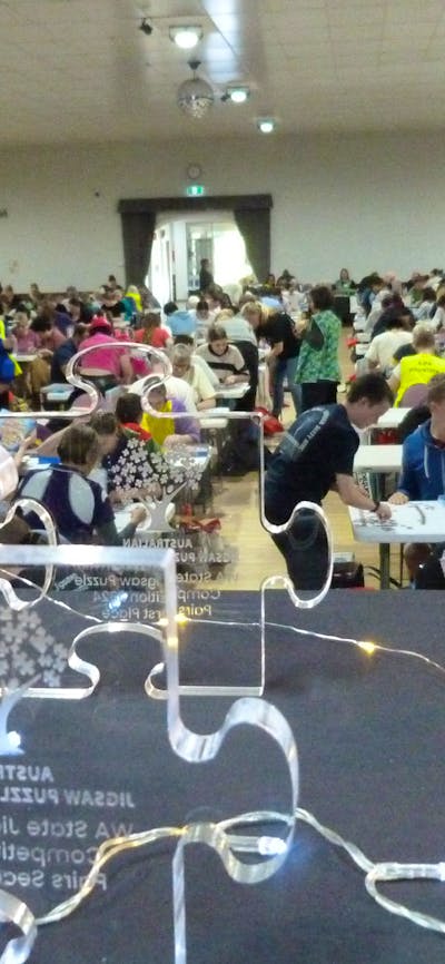 A room full of puzzlers with awards in the foregrounf
