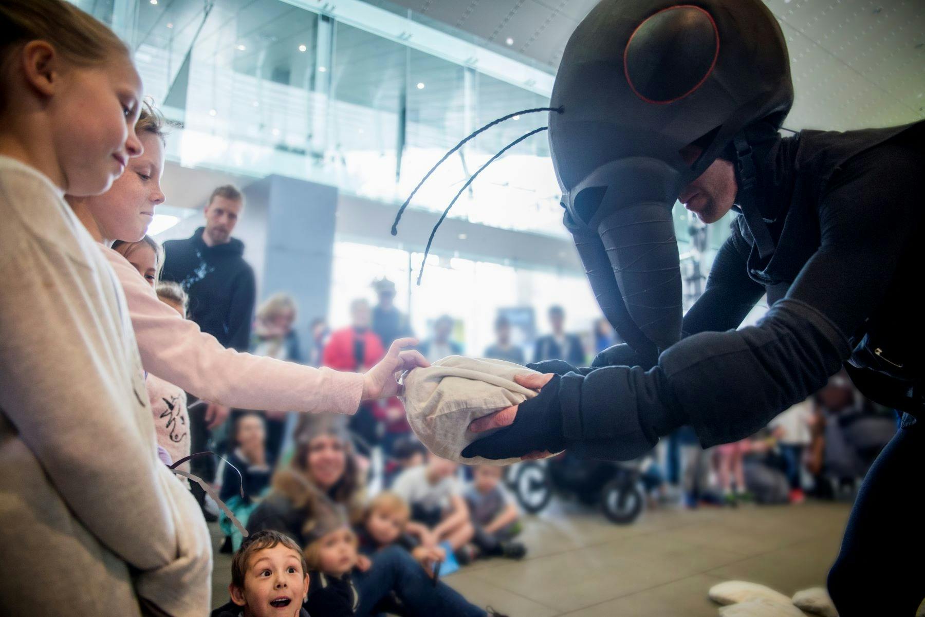 person dressing as ant shaking child hand