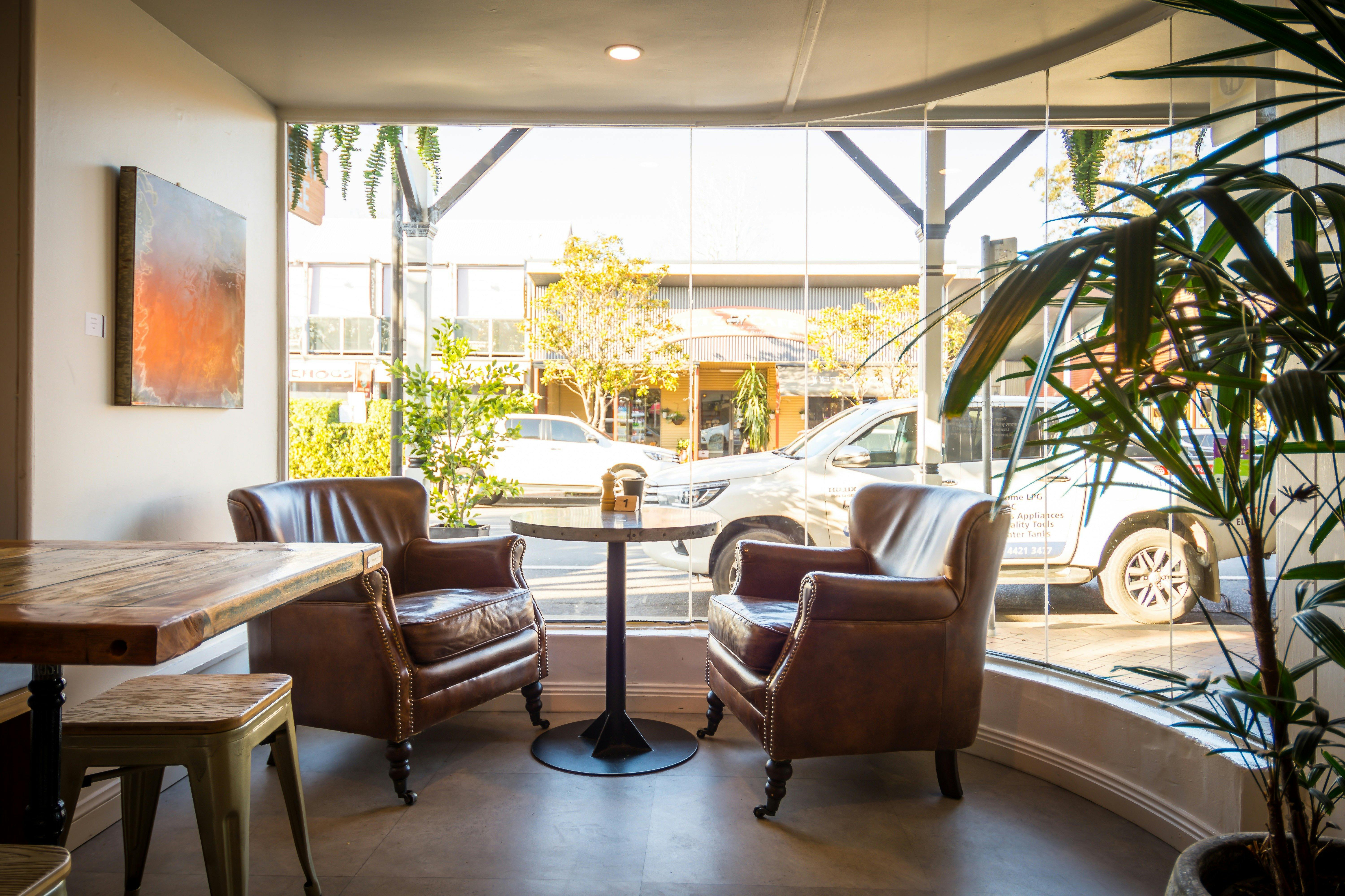 テーブル付きのフロントベイウィンドウの快適なユーズド加工の茶色の革張りのアームチェア