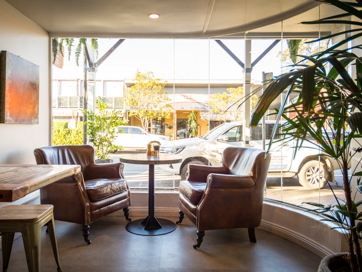 Comfortable distressed brown leather armchairs in the front bay window, with table