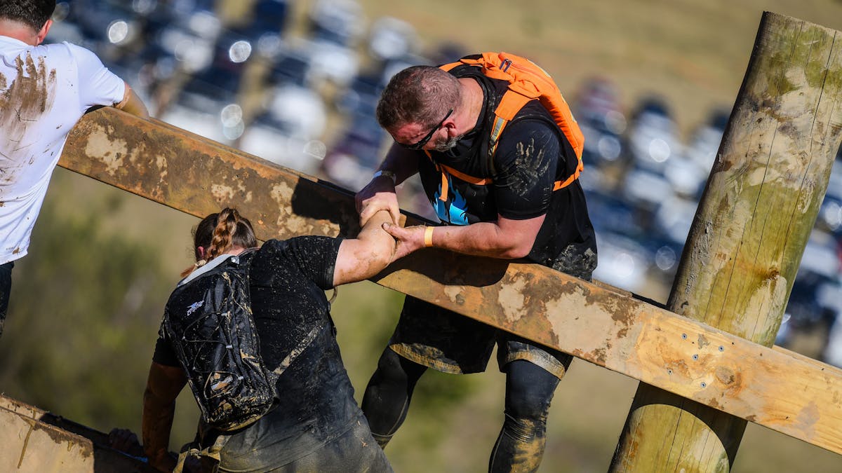 Racer helping another racer over an obstacle