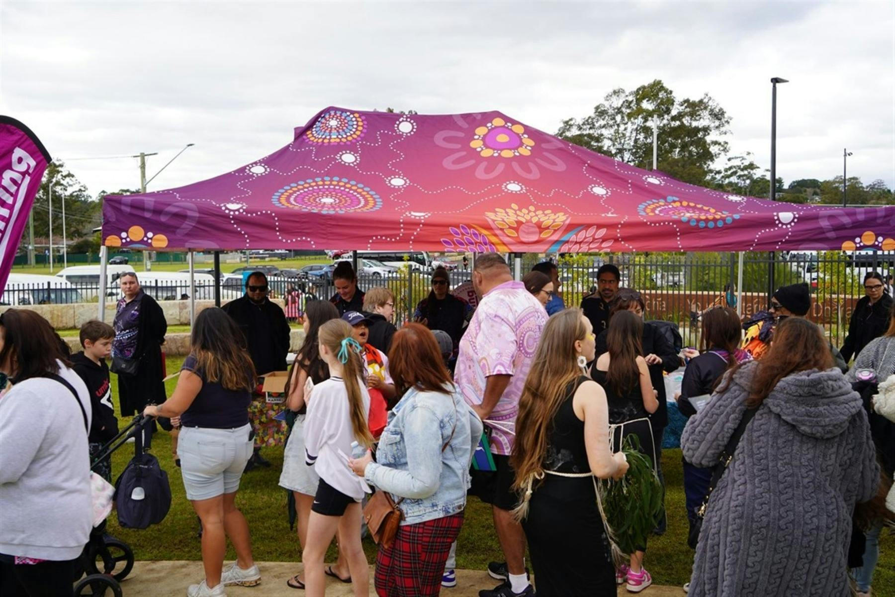 A group of people walking past a market tent