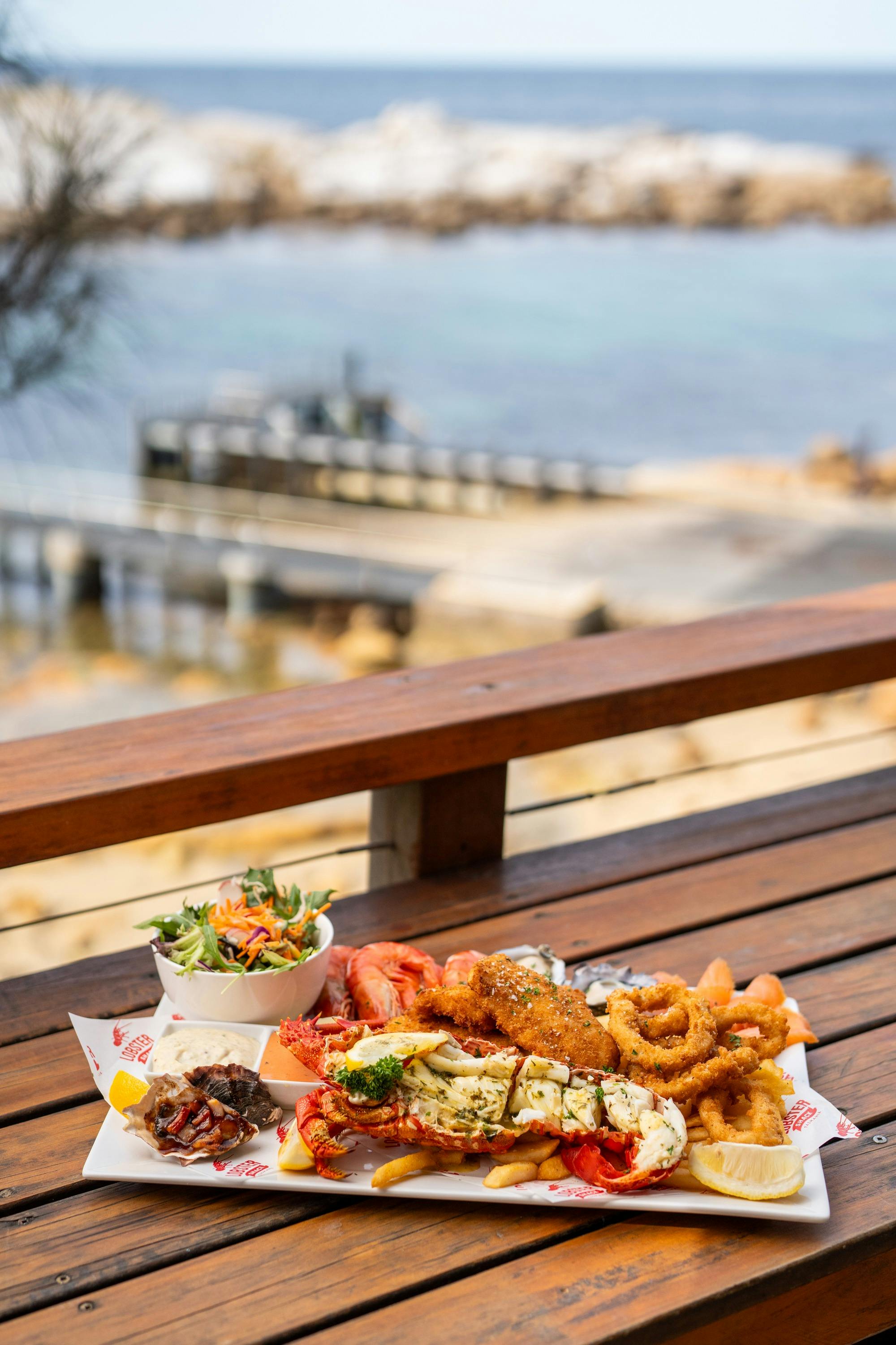 Photo of a seafood platter with a half southern rock lobster served on the oceanfront deck