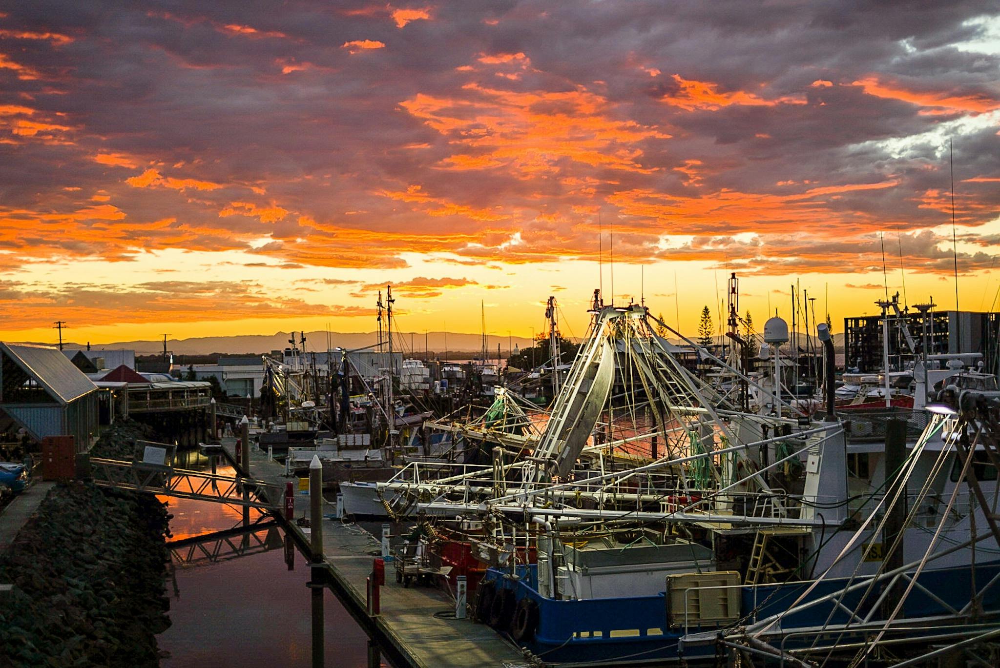 Sunset with colours of orange, red and purple hitting the clouds. Looking over the fishing trawlers