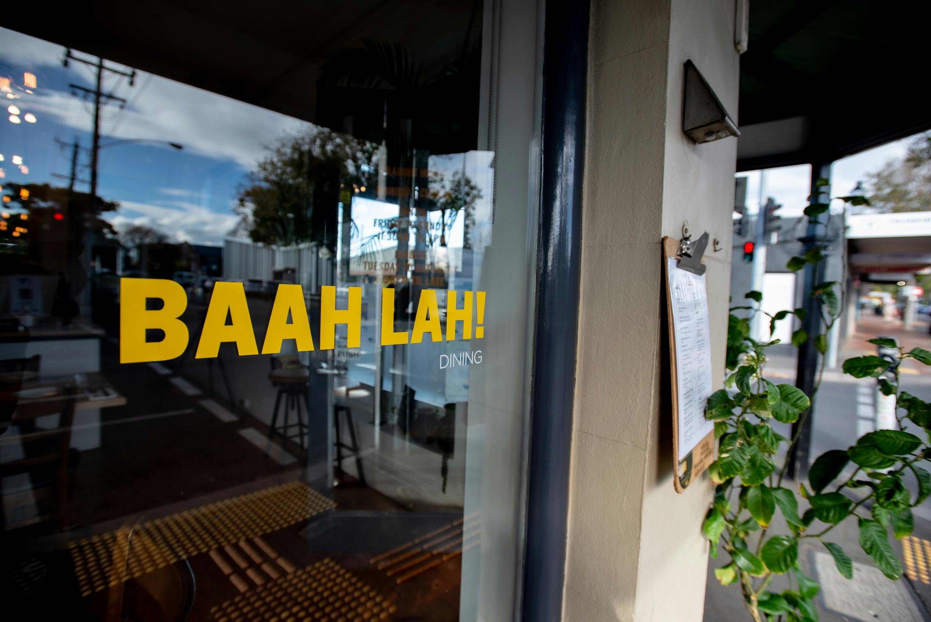 Front window, with decals in yellow 'BAAH LAH! Dining" outdoor menu on street front and a lemon tree