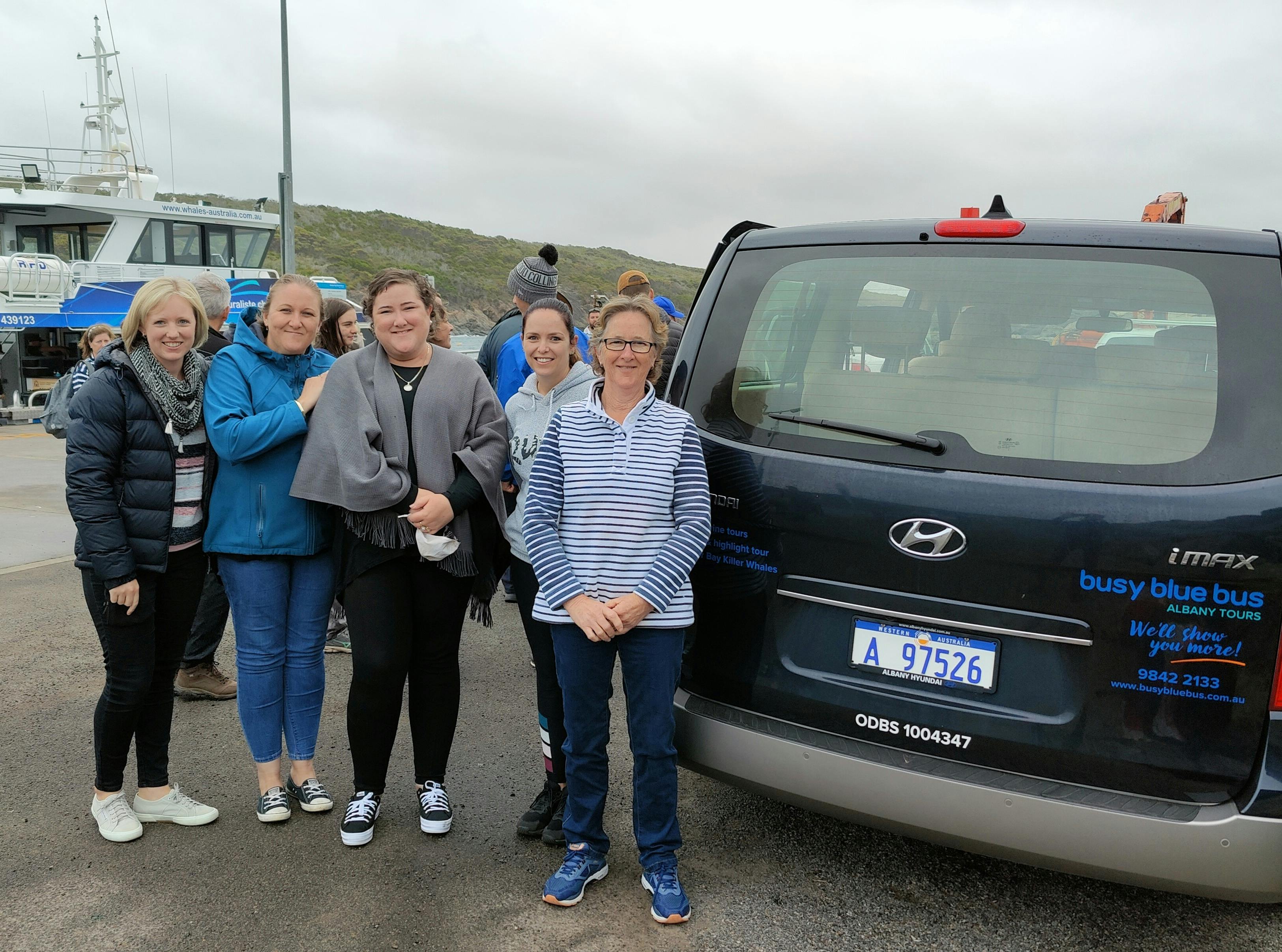 fice women at rear of vehicle in front of boat at jetty