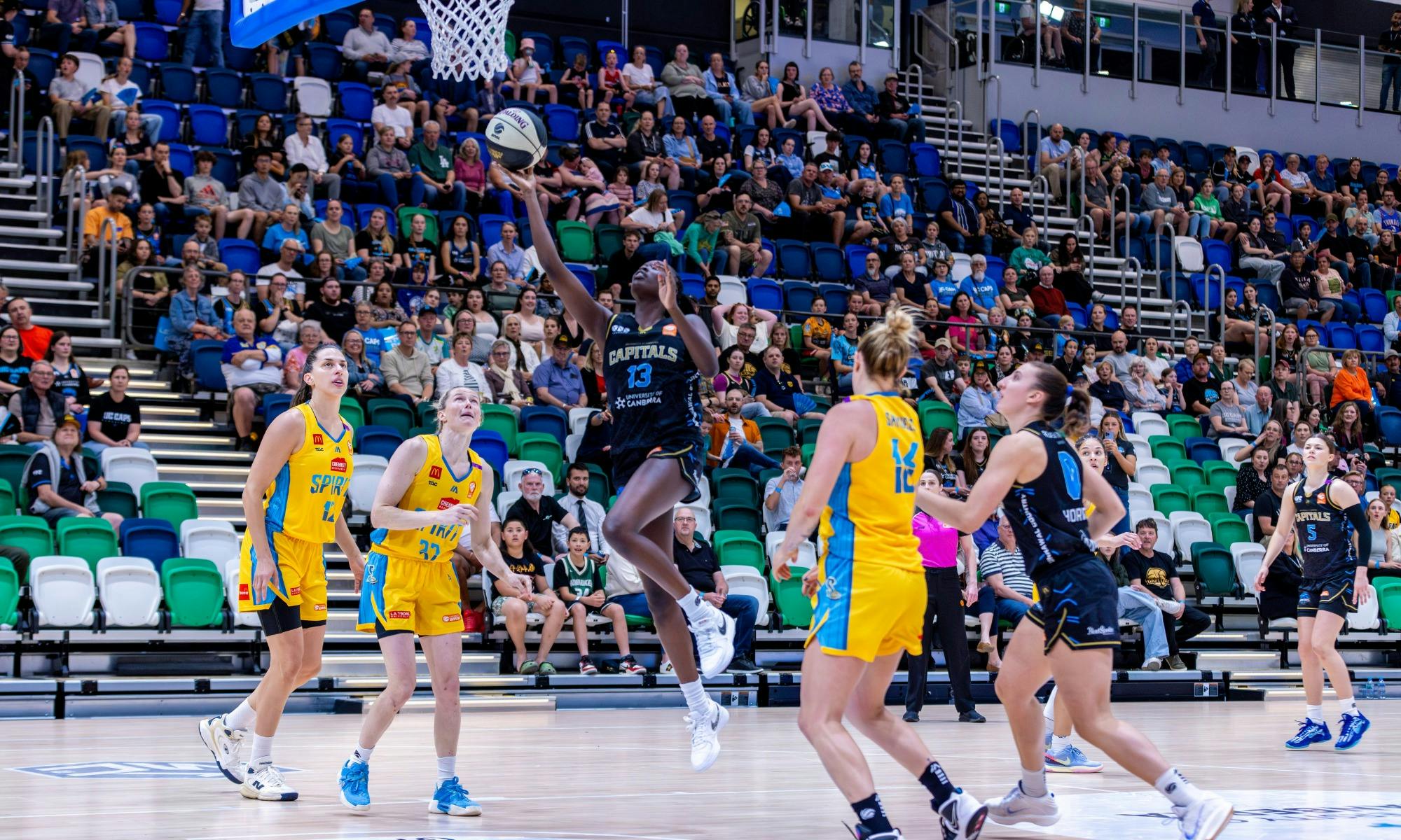 UC Capitals player driving to the basket for a layup during a WNBL game.