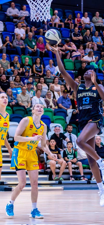 UC Capitals player driving to the basket for a layup during a WNBL game.