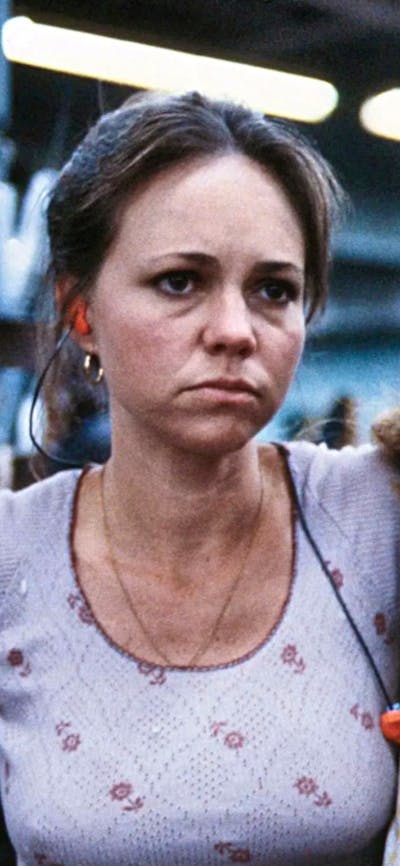 Two women look tired, one has arm over the other both looking to their left towards something