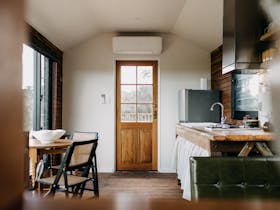 View of the front door and kitchen space with a large timber bench and retro seating area