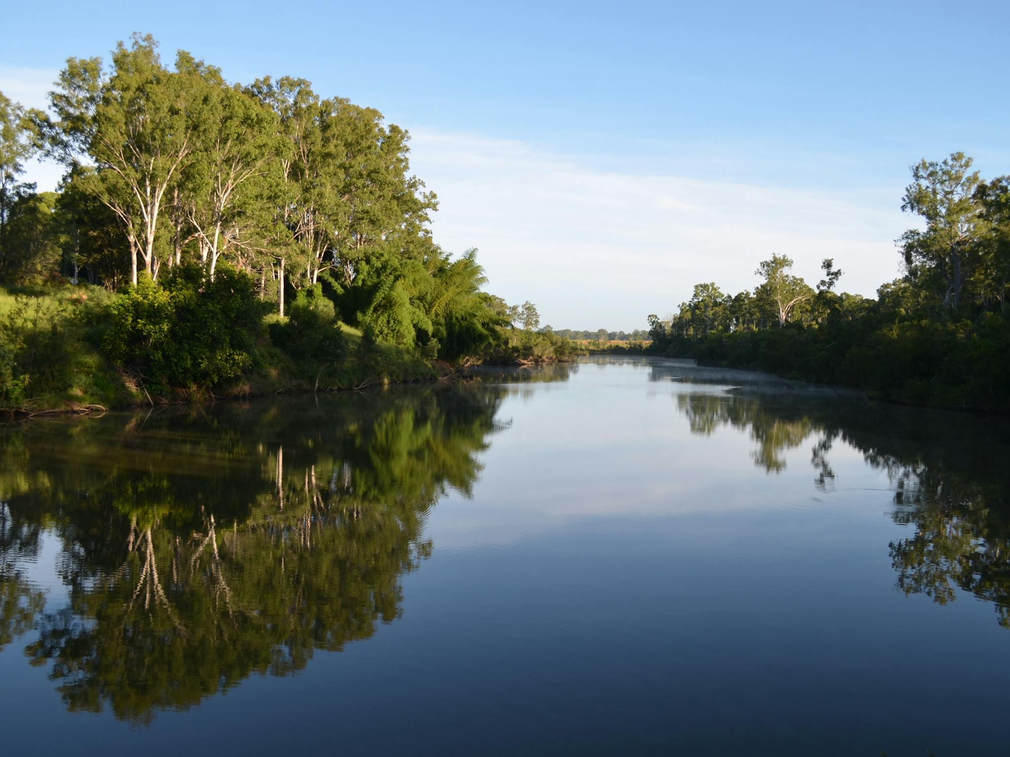 photo showing the Mary River at Tiaro with a calm reflective surface and lined by trees photo showing the Mary River at Tiaro with a calm reflective surface and lined by trees