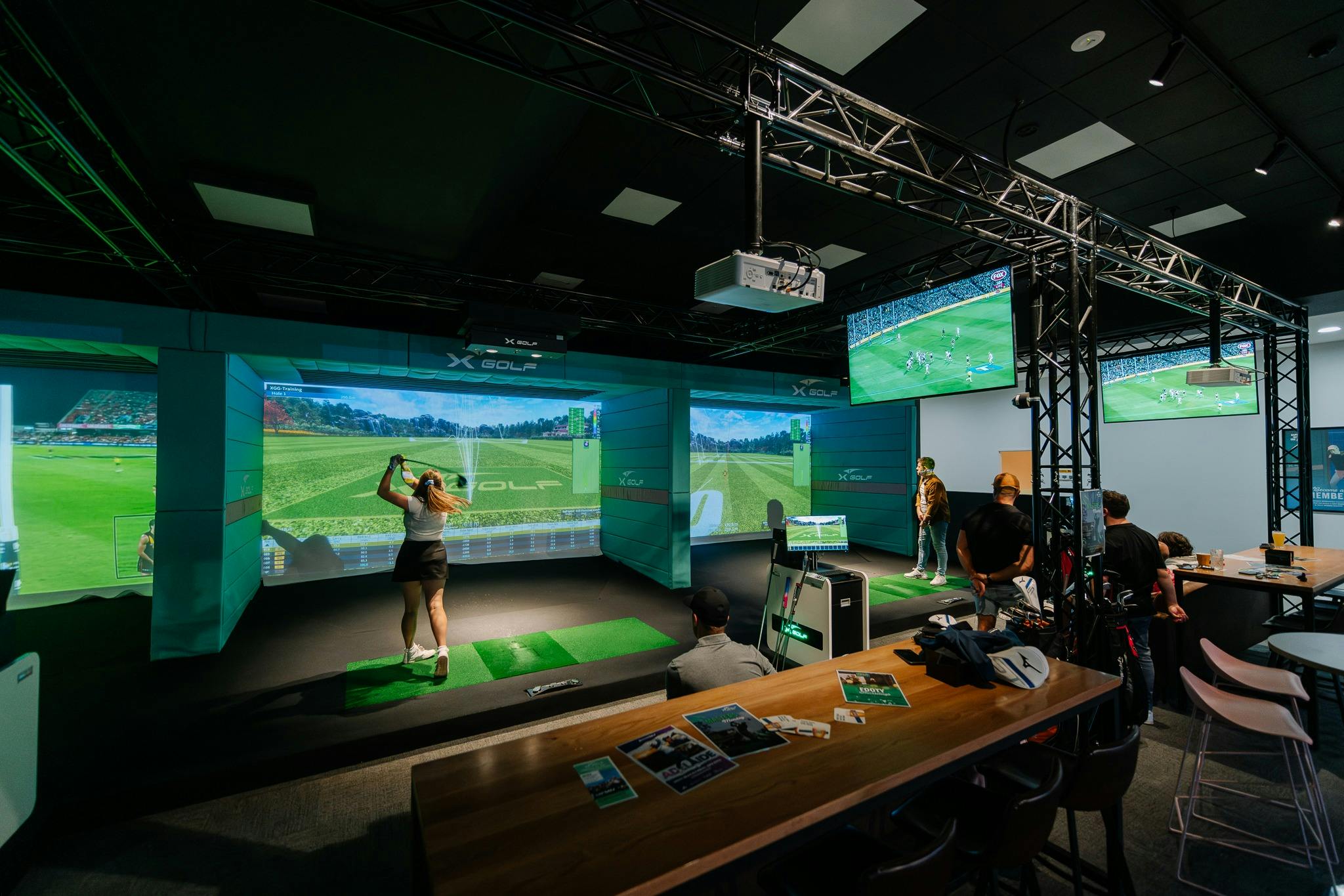 A woman in a golf skirt hits a golf ball indoors