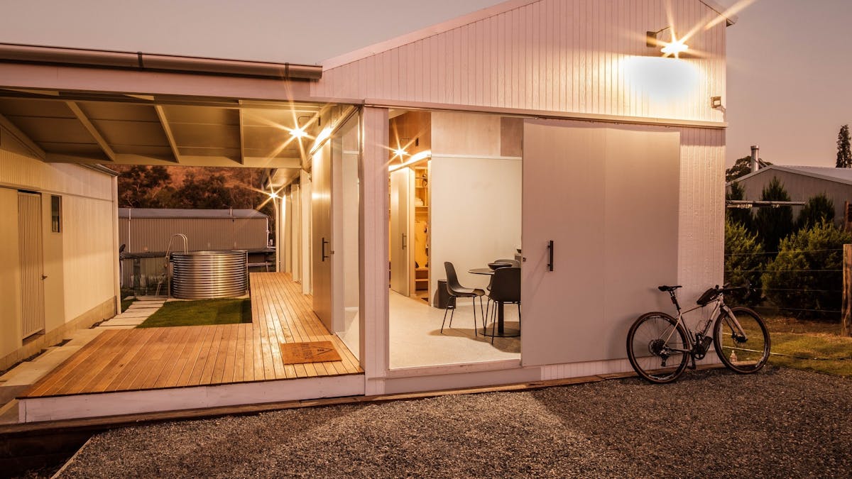 Accom lit up at evening with pluge pool in the back, bike at the front and lights on