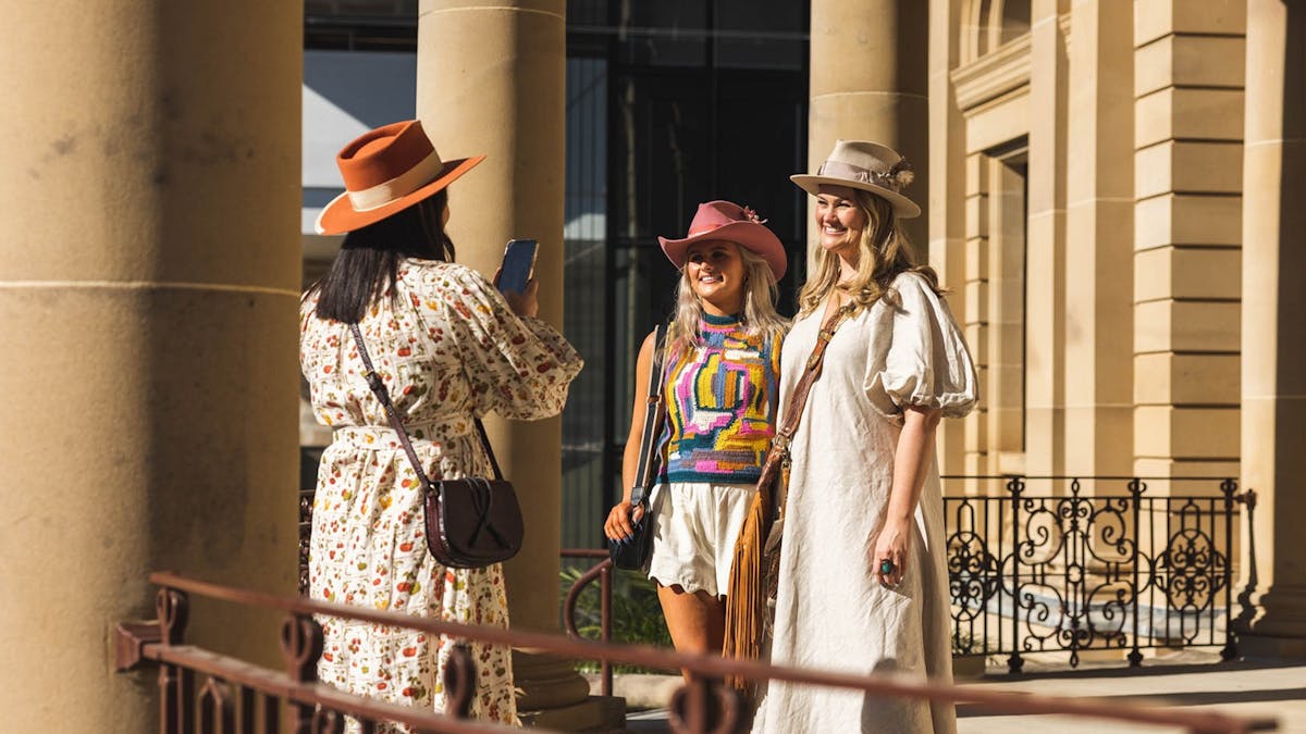 Three young women taking photos up on Customs House in the morning sun.
