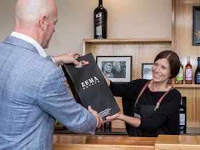 Woman give man a bottle of wine