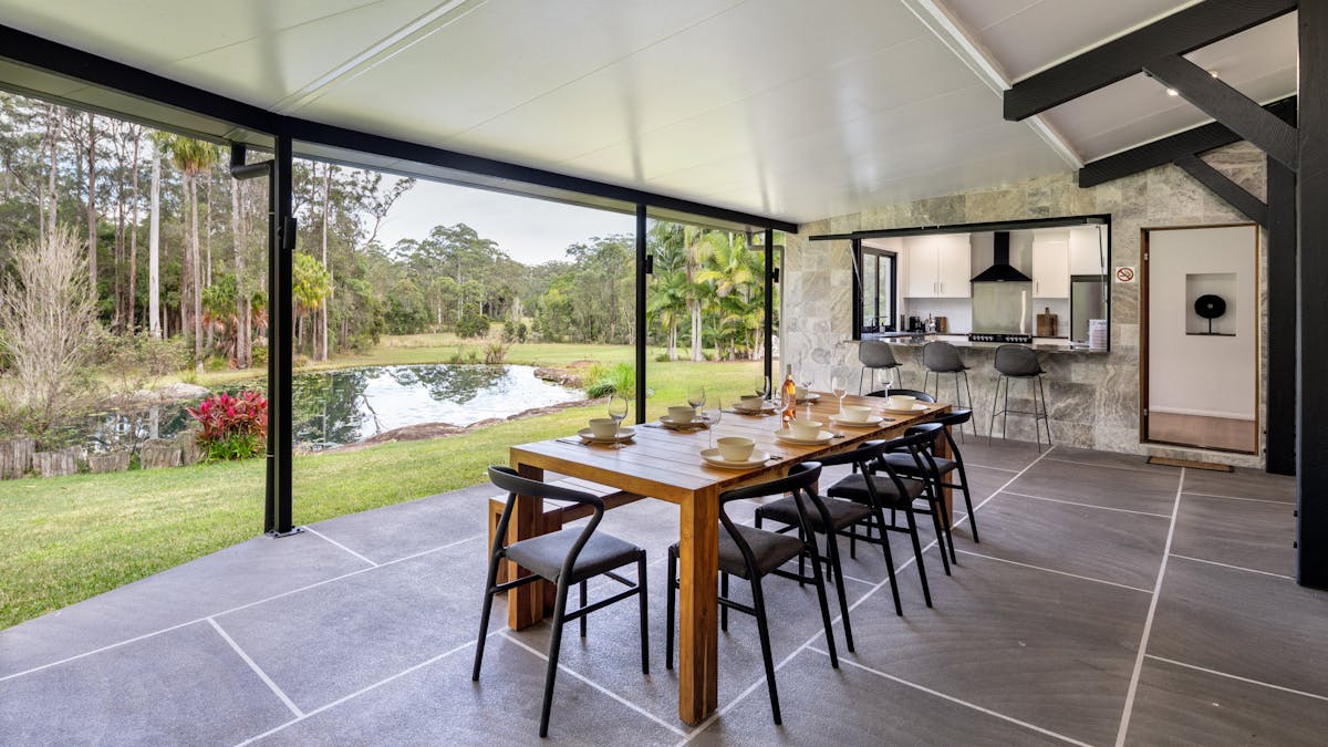 Large outdoor seating with a BBQ that overlooks the pond and rainforest.