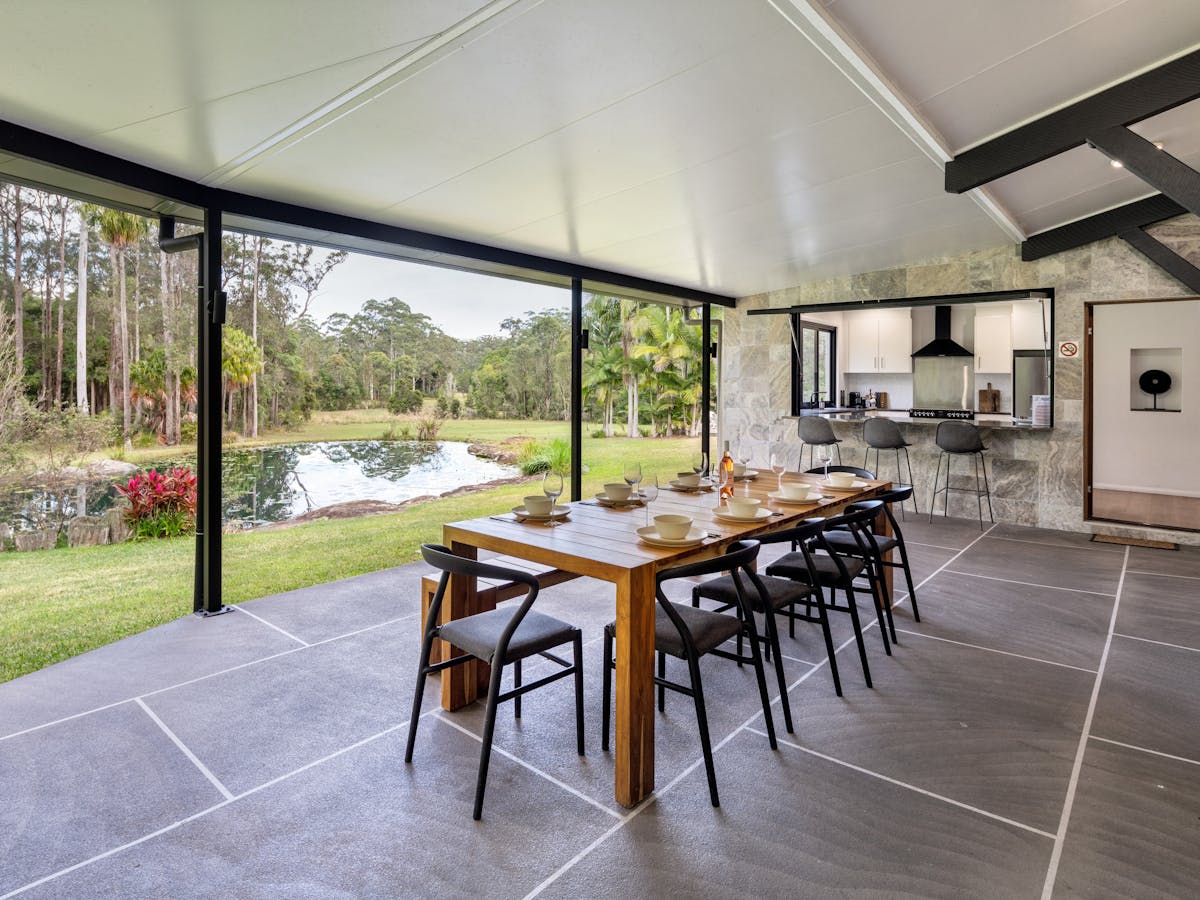 Large outdoor seating with a BBQ that overlooks the pond and rainforest.