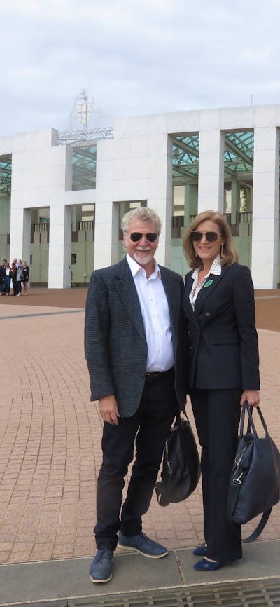 A man and a woman standing in front of the Parliament House in Canberra