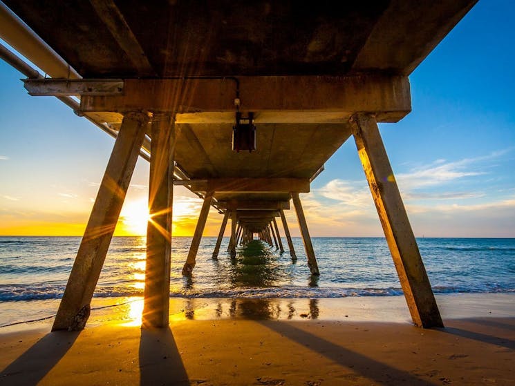photograph taken underneath the Coffs Harbour Jetty, looking out toward the ocean at sunrise