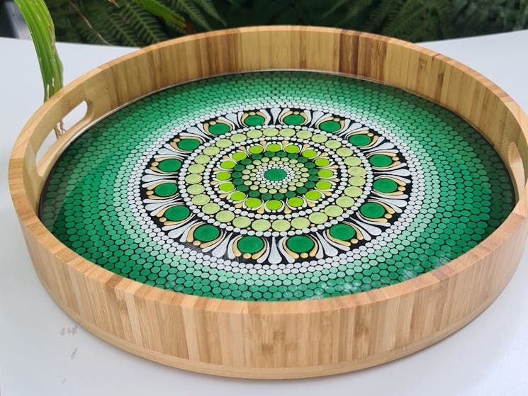 A pale timber serving platter with a green dot art design