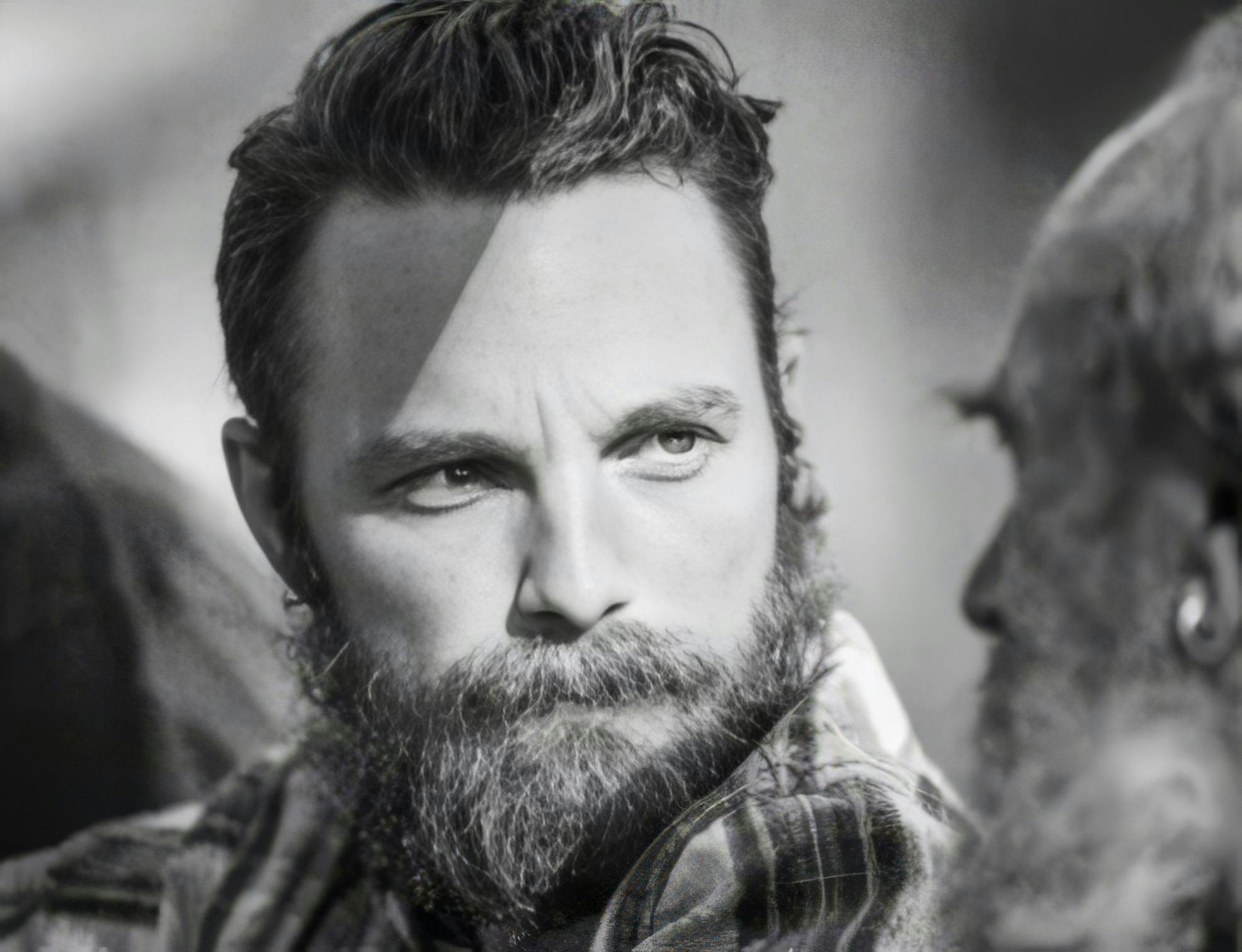 A man with a beard looking towards an older man, deep in thought