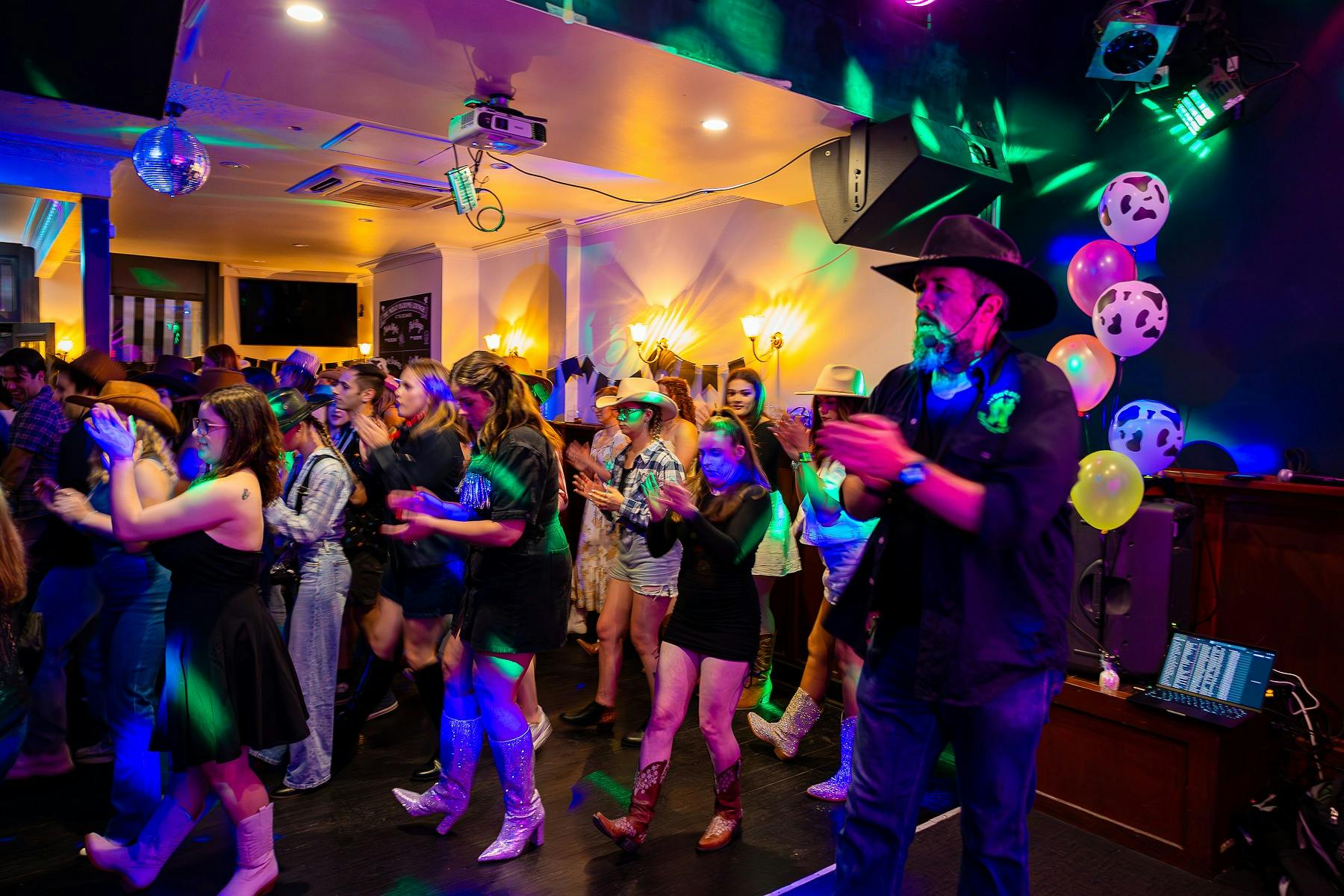 a room full of booscooting dancers with coloured neon lights