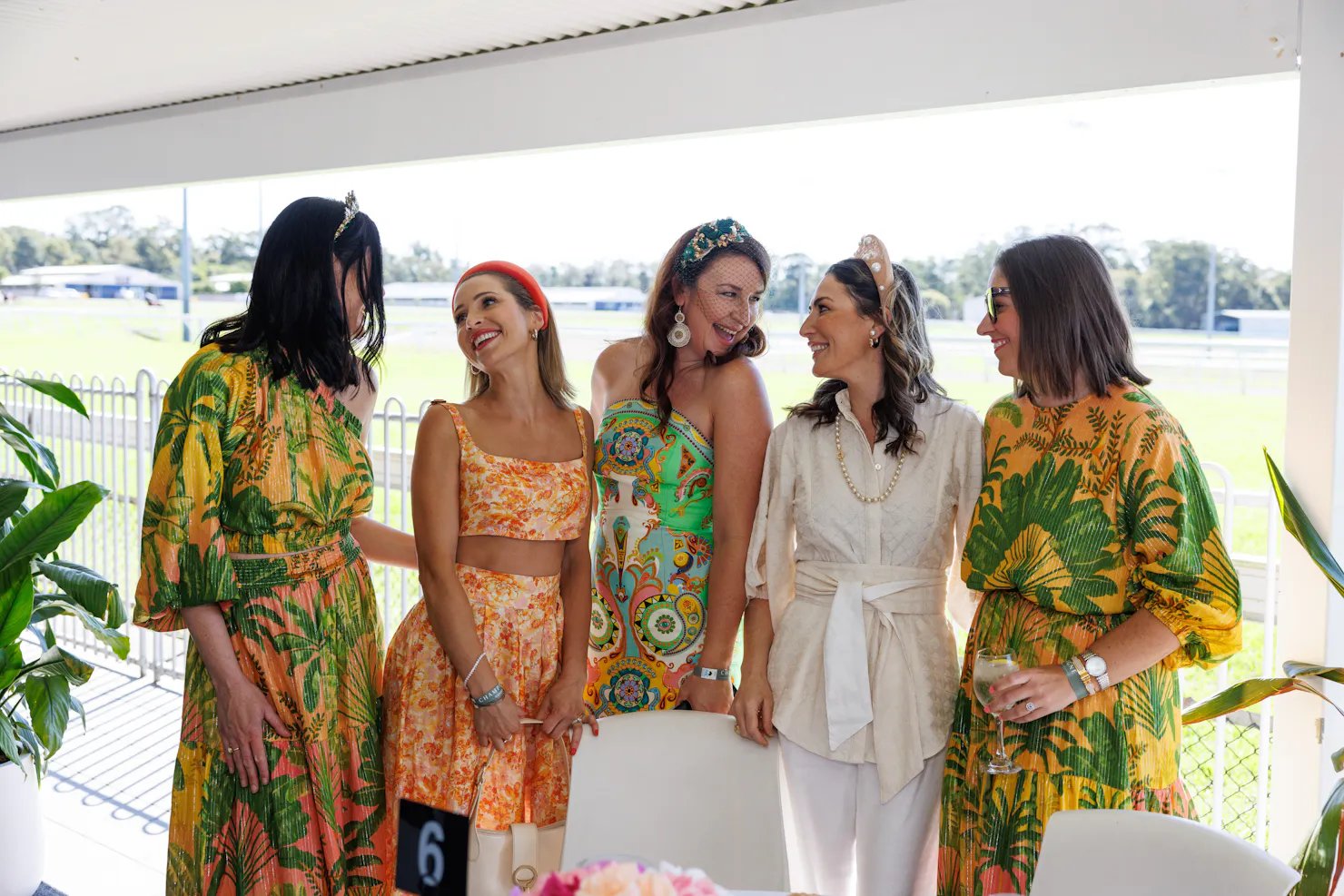 Five women dressed in racewear smiling and laughing  at each other