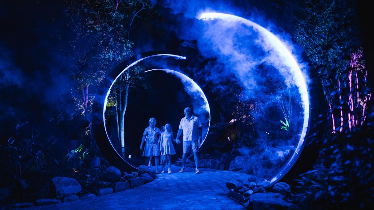 Family walking through blue illuminated archways with smoke effects.