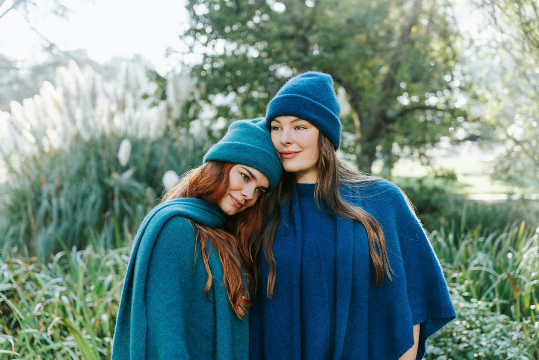 Two women wearing beanies, scarves and ponchos