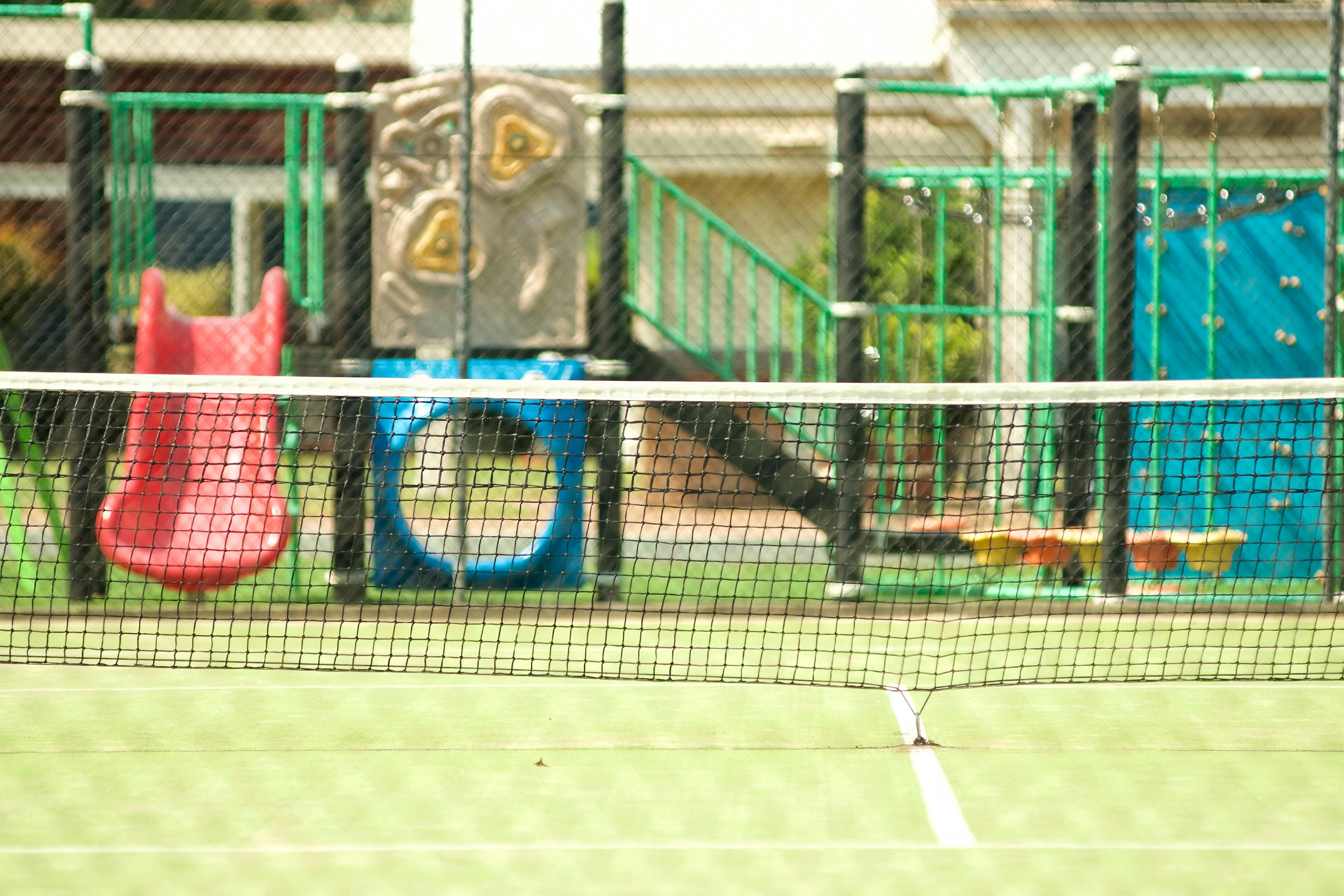 Tennis courts are next to playground and pool house