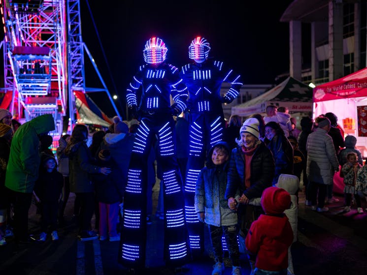 Lit up stiltwalking robots entertaining crowds at the festival.