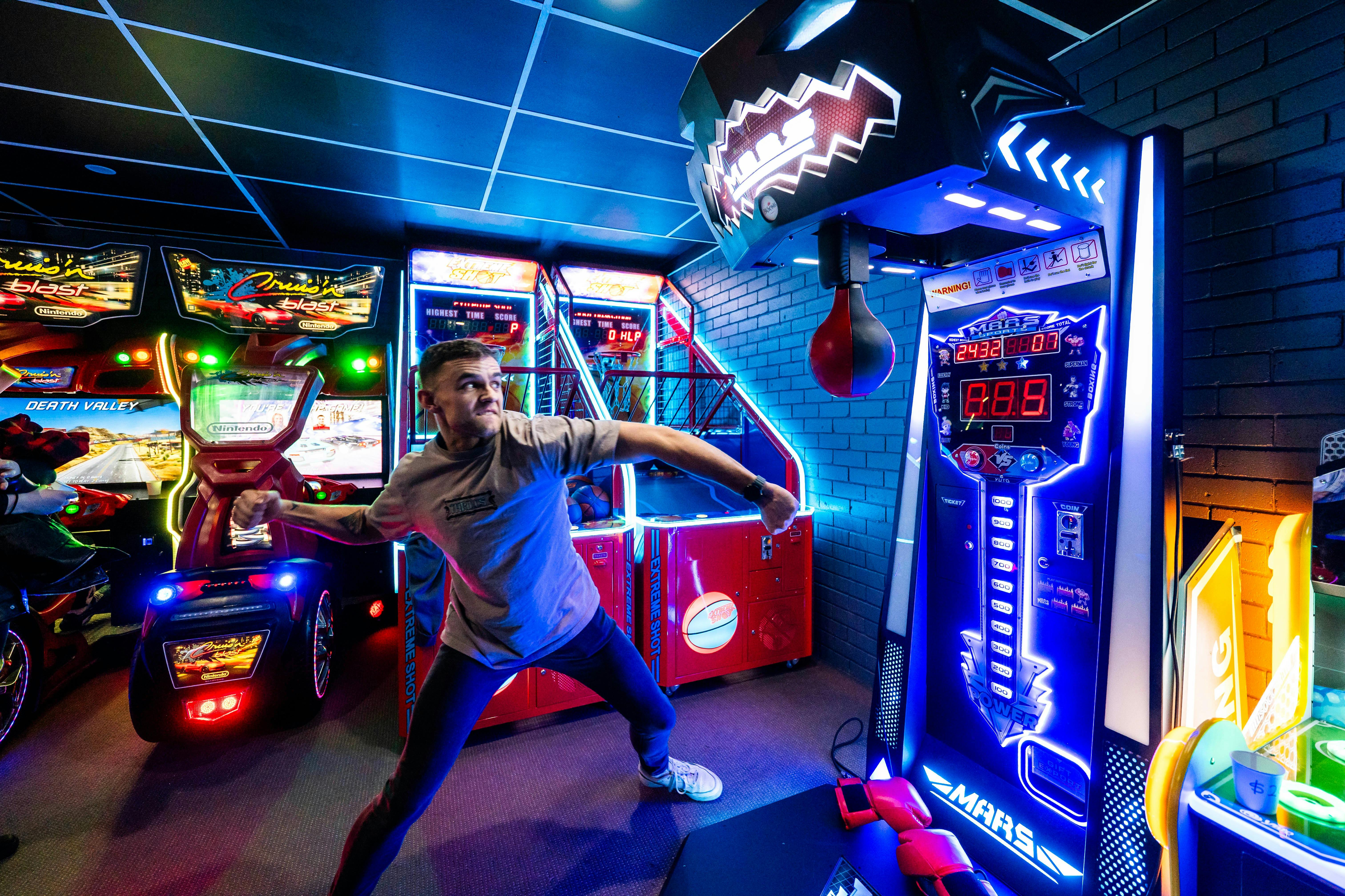 Person playing Mars Boxing machine in a neon-lit game room